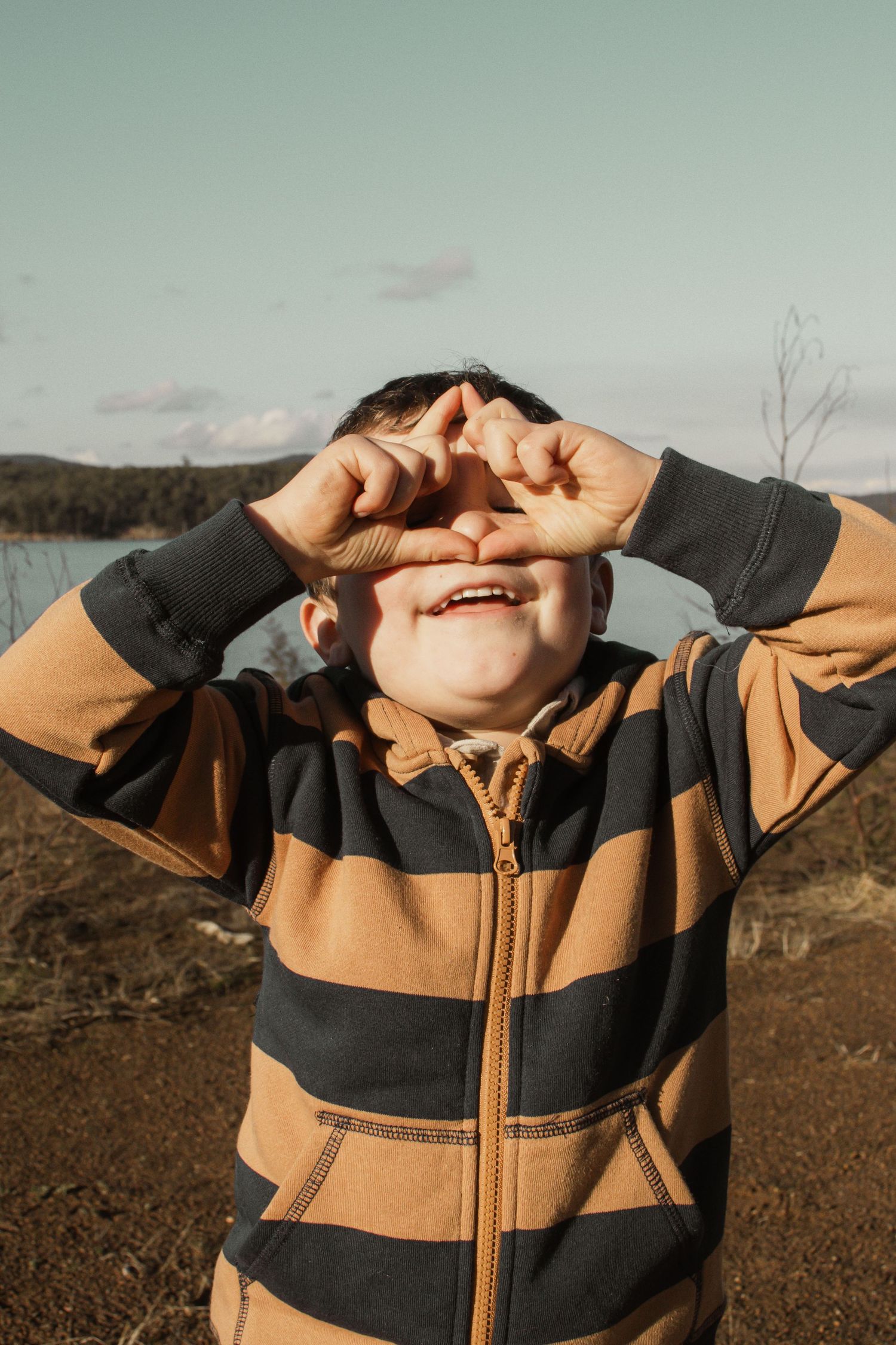 A child making binoculars at blue rock lake with family in the outdoors in central Gippsland. Taken for a motherhood/pet session.