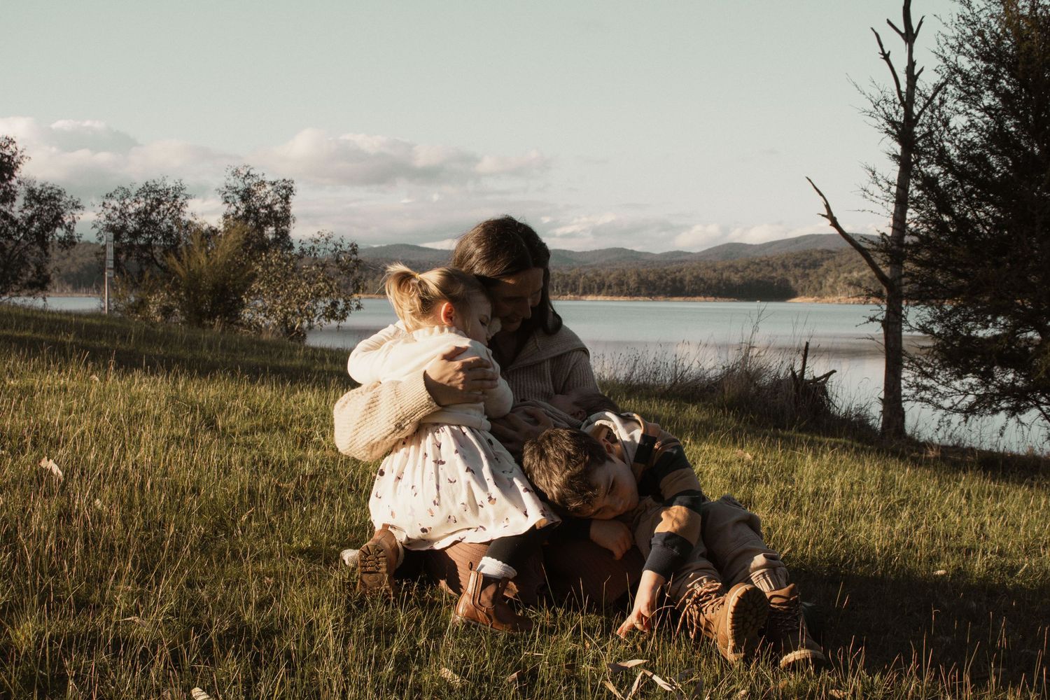 A family cuddling together at blue rock lake in the outdoors in central Gippsland. Taken for a motherhood/pet session.