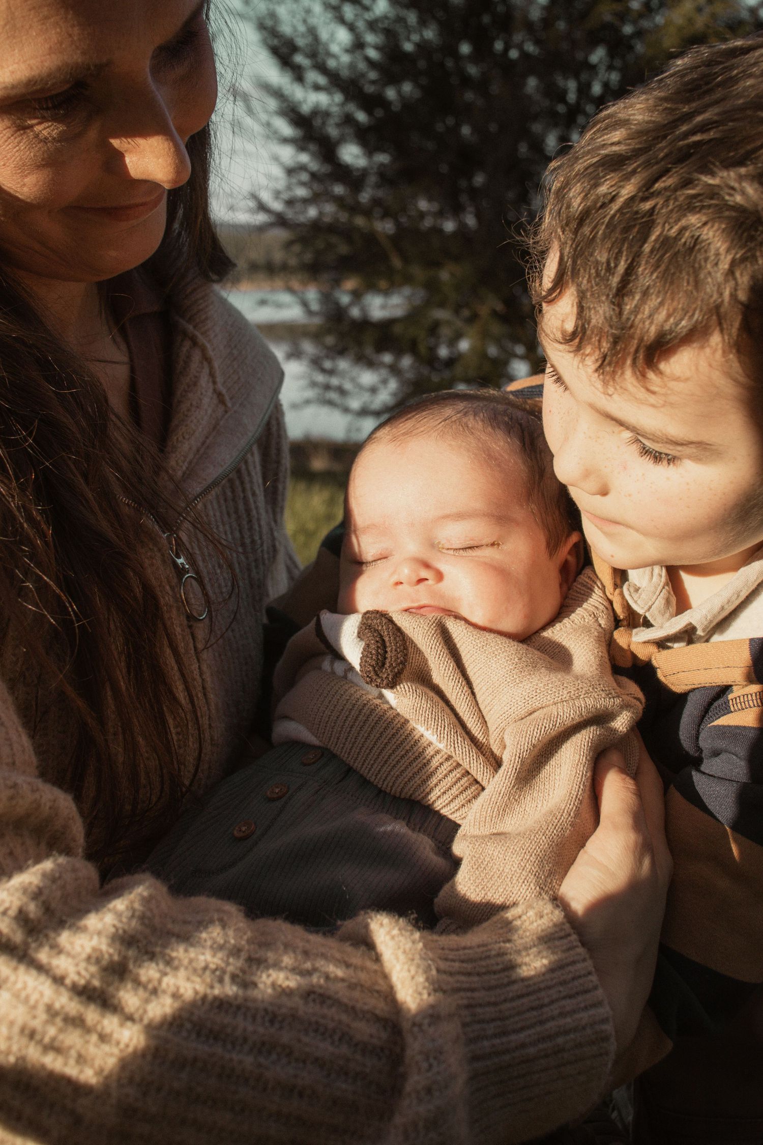 A family cuddling together at blue rock lake in the outdoors in central Gippsland. Taken for a motherhood/pet session.