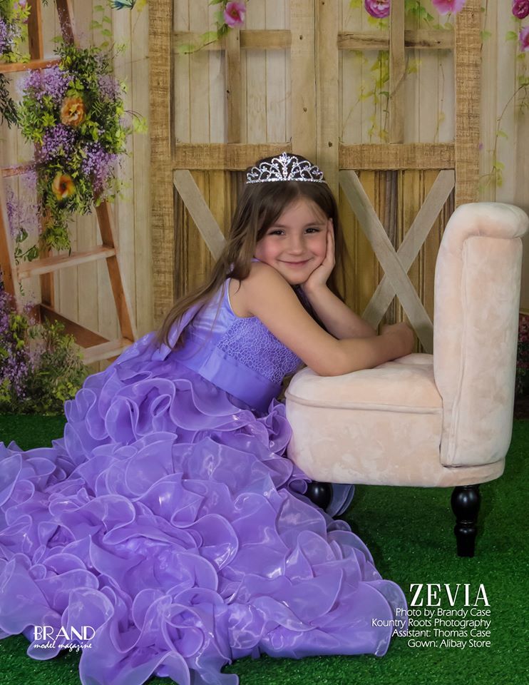 Purple princess dress portrait in decorated garden setting with wooden backdrop.