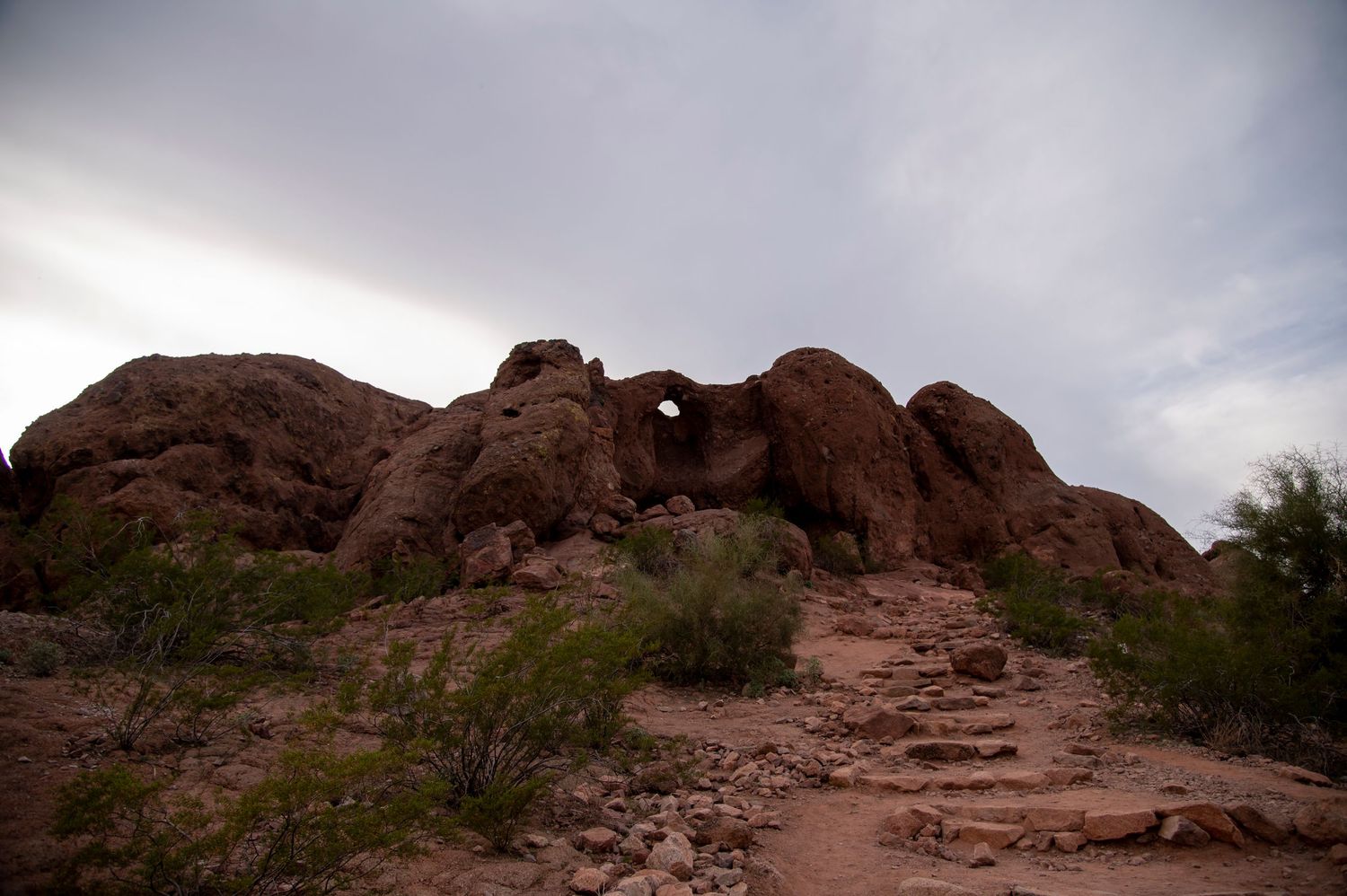 Panoramic view of red rock formations and desert landscape under a cloudy sky.