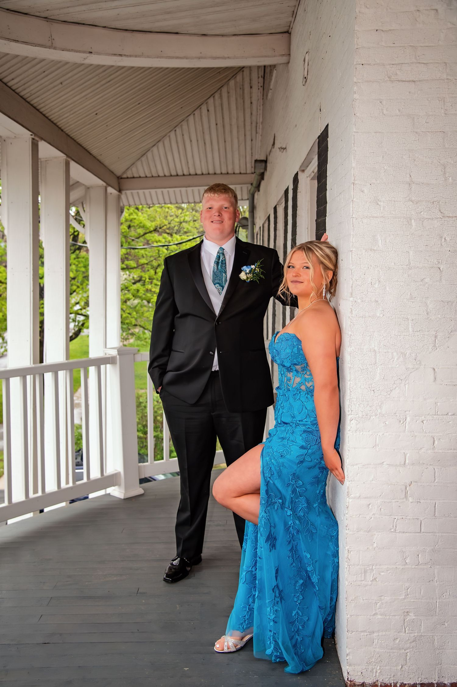 Elegant prom photo shoot in a white columned corridor with dramatic lighting.