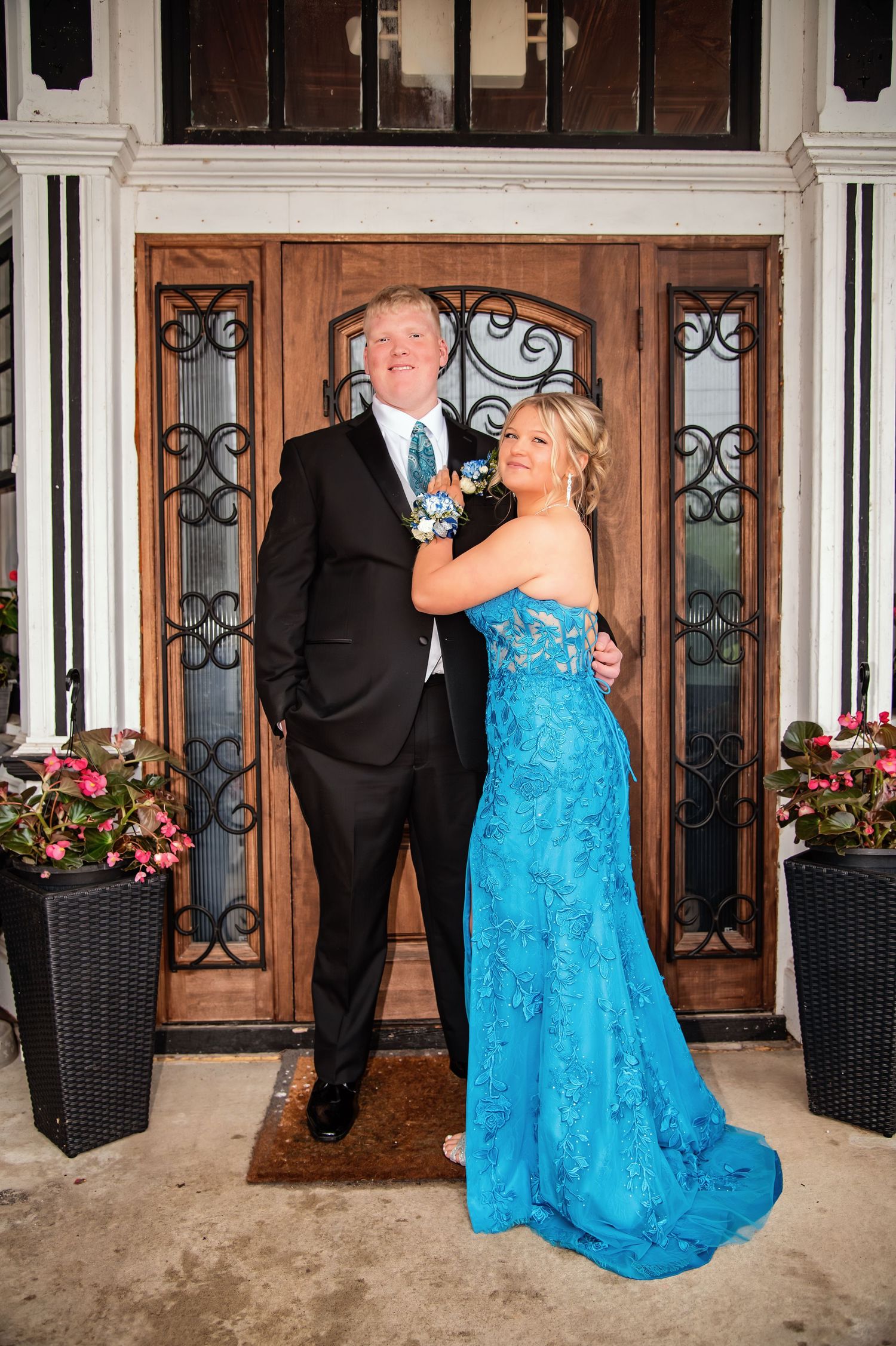 Formal event photography against ornate wooden doors with decorative ironwork and planters.