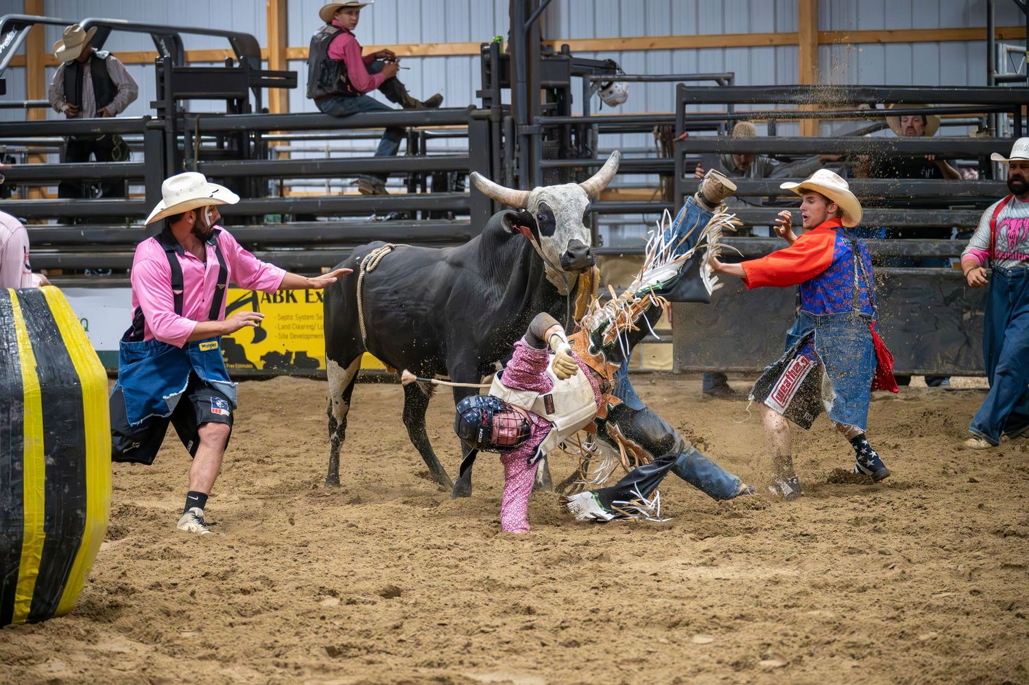Children participating in rodeo activities in an indoor arena with safety equipment.