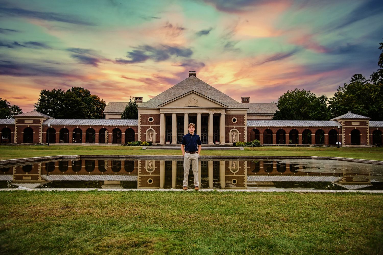 Panoramic view of a stately white colonial style building with columns and symmetrical architecture at sunset.