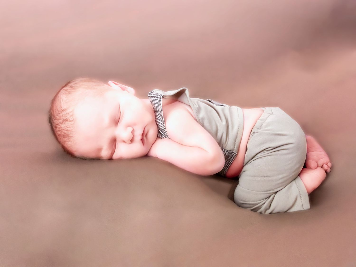 Close-up details of a sleeping newborn baby wrapped in gray swaddling cloth.