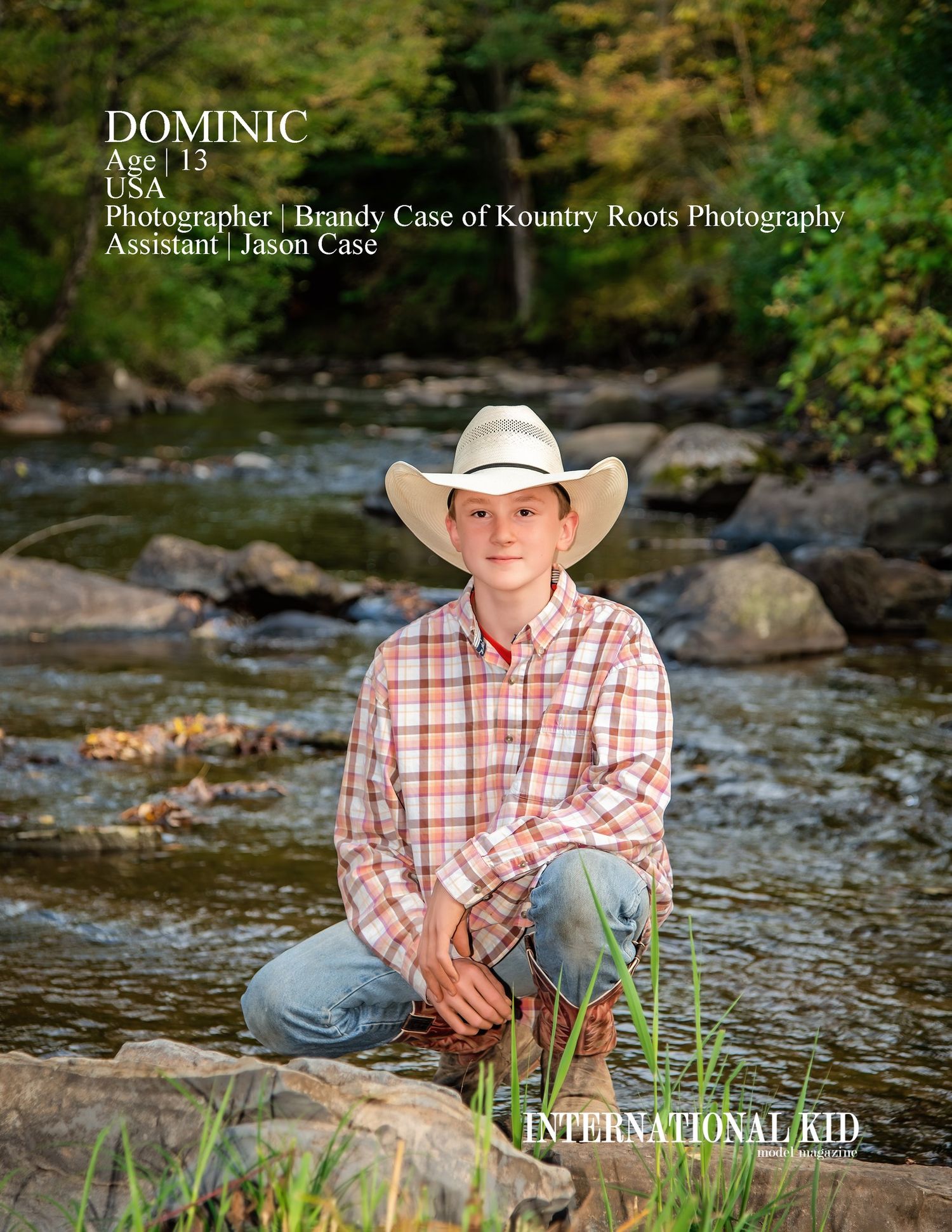 A young person in plaid shirt and cowboy hat crouches by a rocky stream.