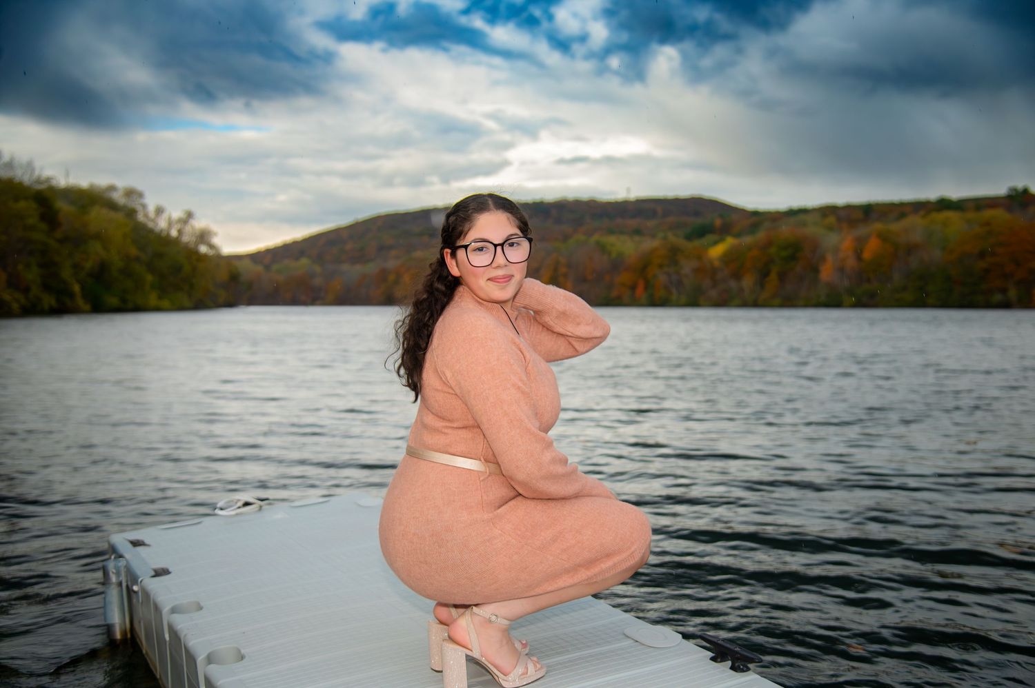 Scenic lakeside photoshoot with mountains and cloudy sky in background.