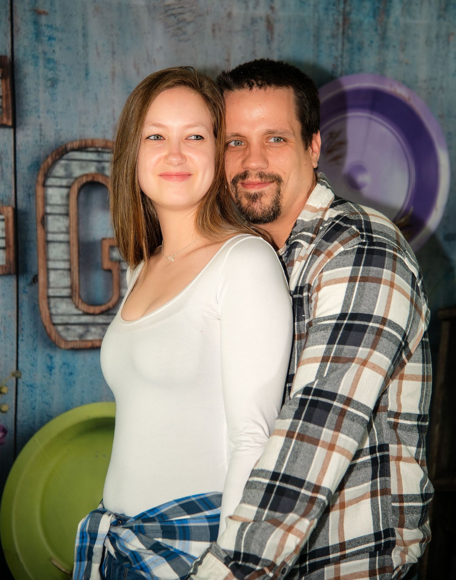 Casual indoor photoshoot against blue industrial wall with decorative plates.
