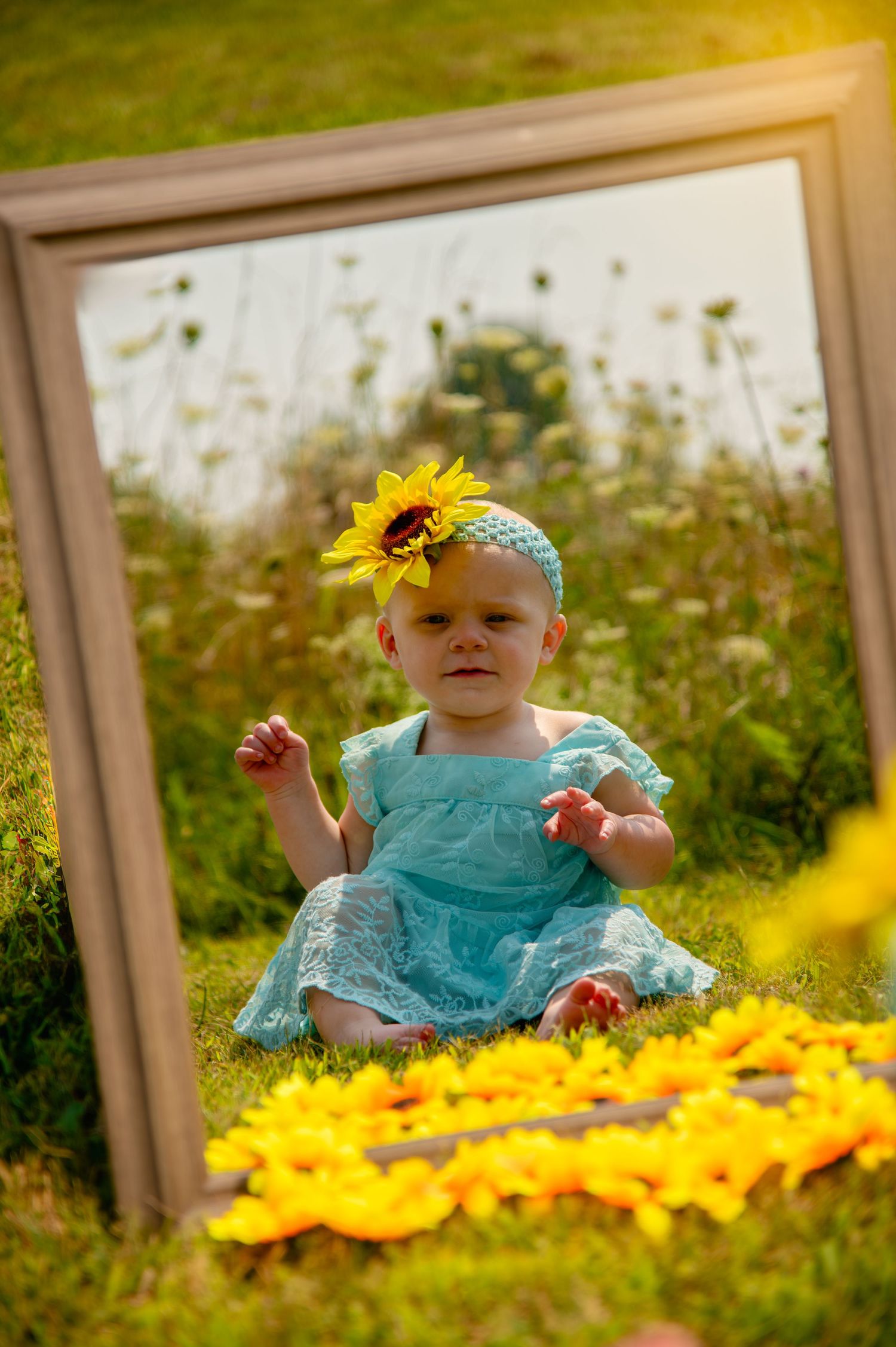 A turquoise dress stands out among bright yellow flowers in a sunlit garden setting.