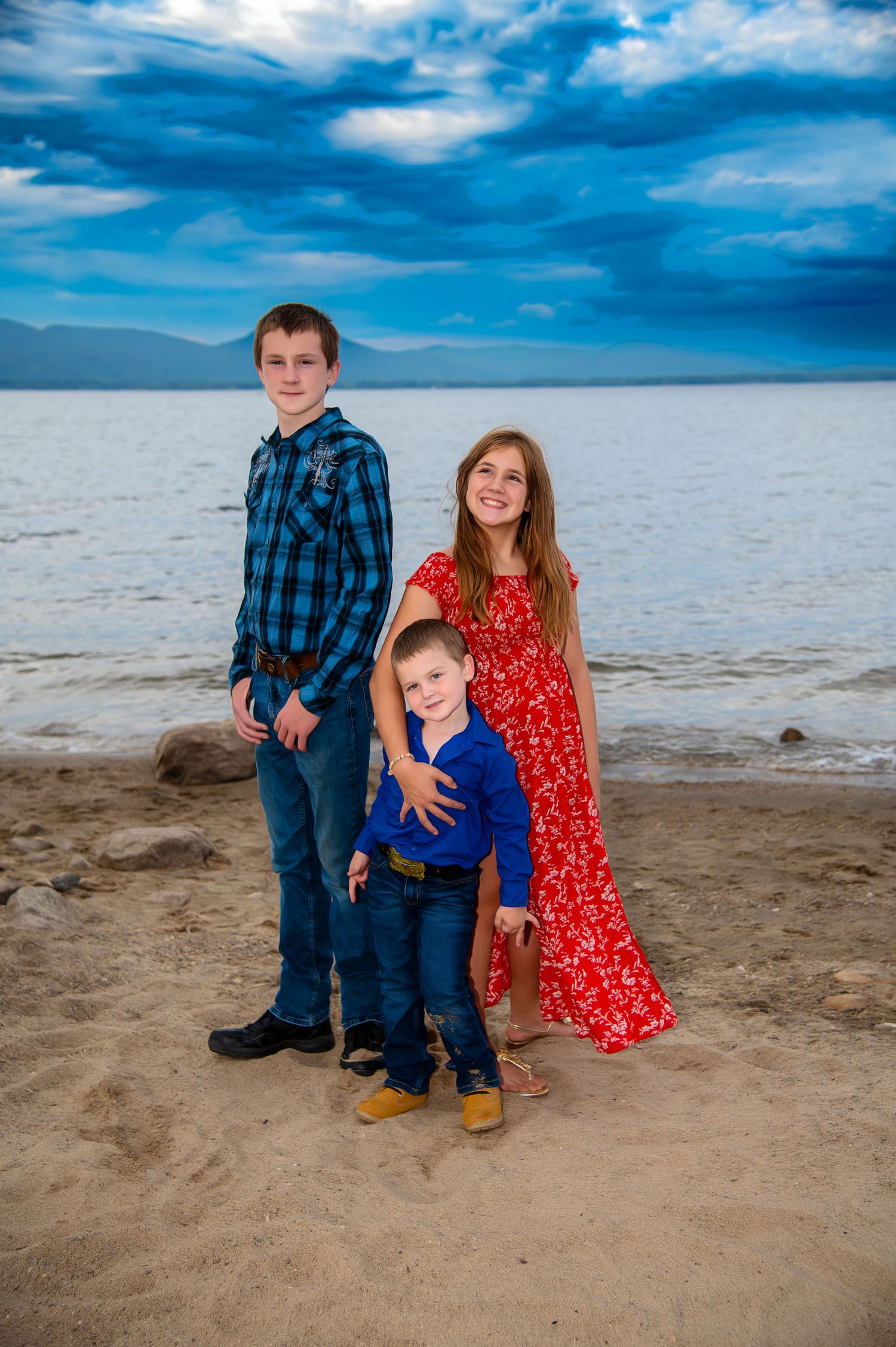 Beach family portrait session with dramatic blue sky and sandy shoreline.
