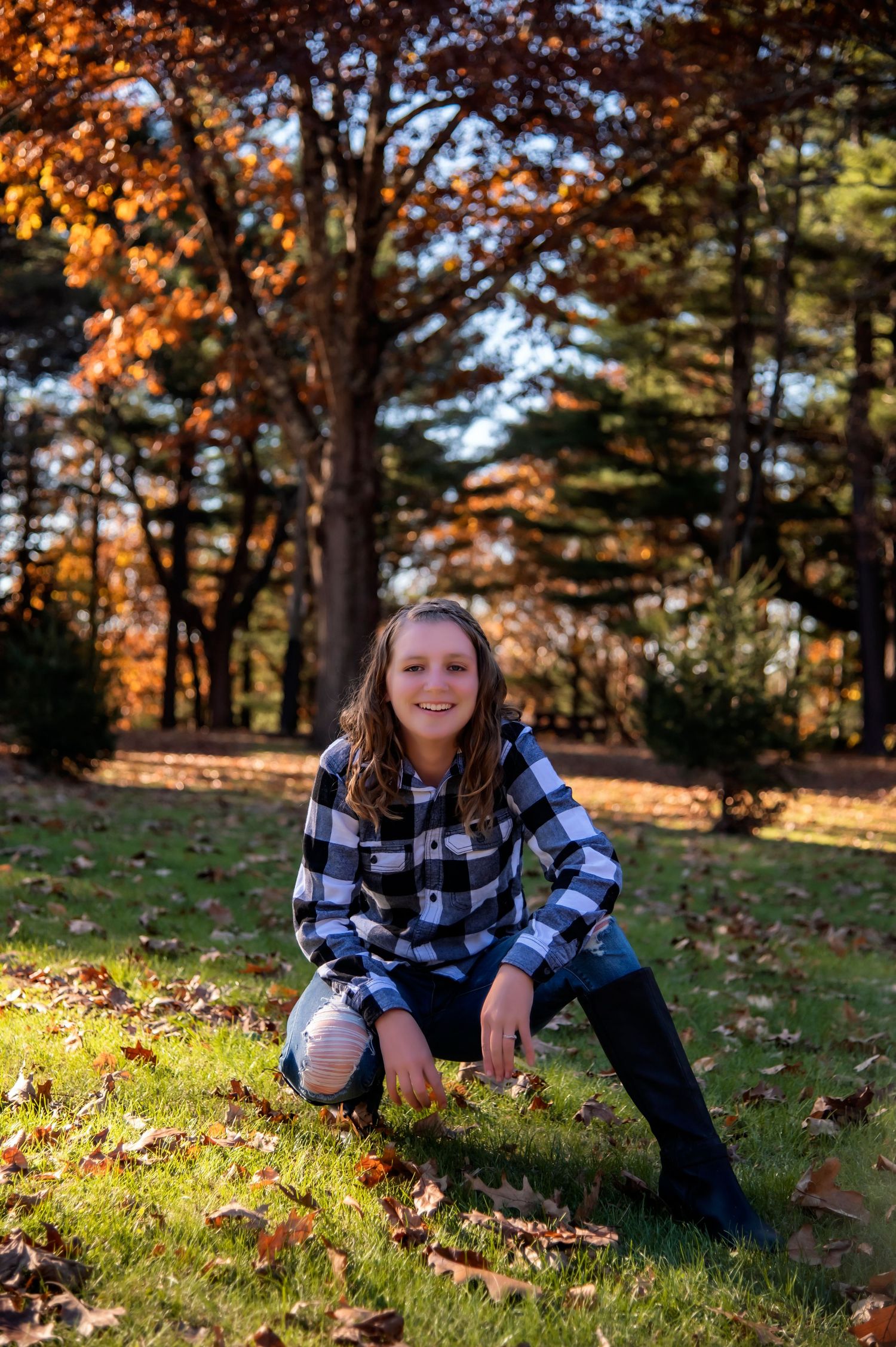 Autumn portrait session in park with fallen leaves and golden sunlight.