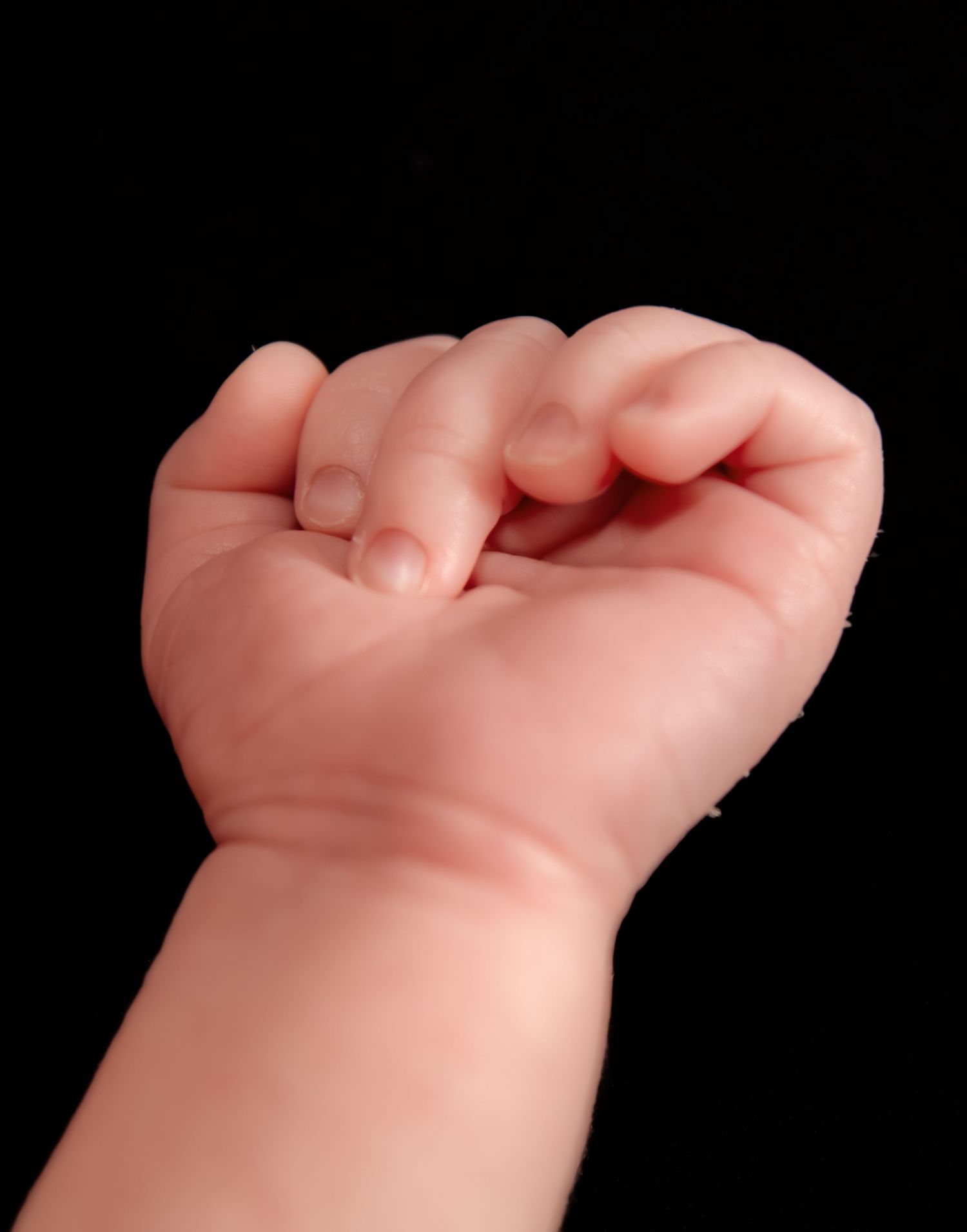 Artistic macro shots of newborn baby fingers against black background.