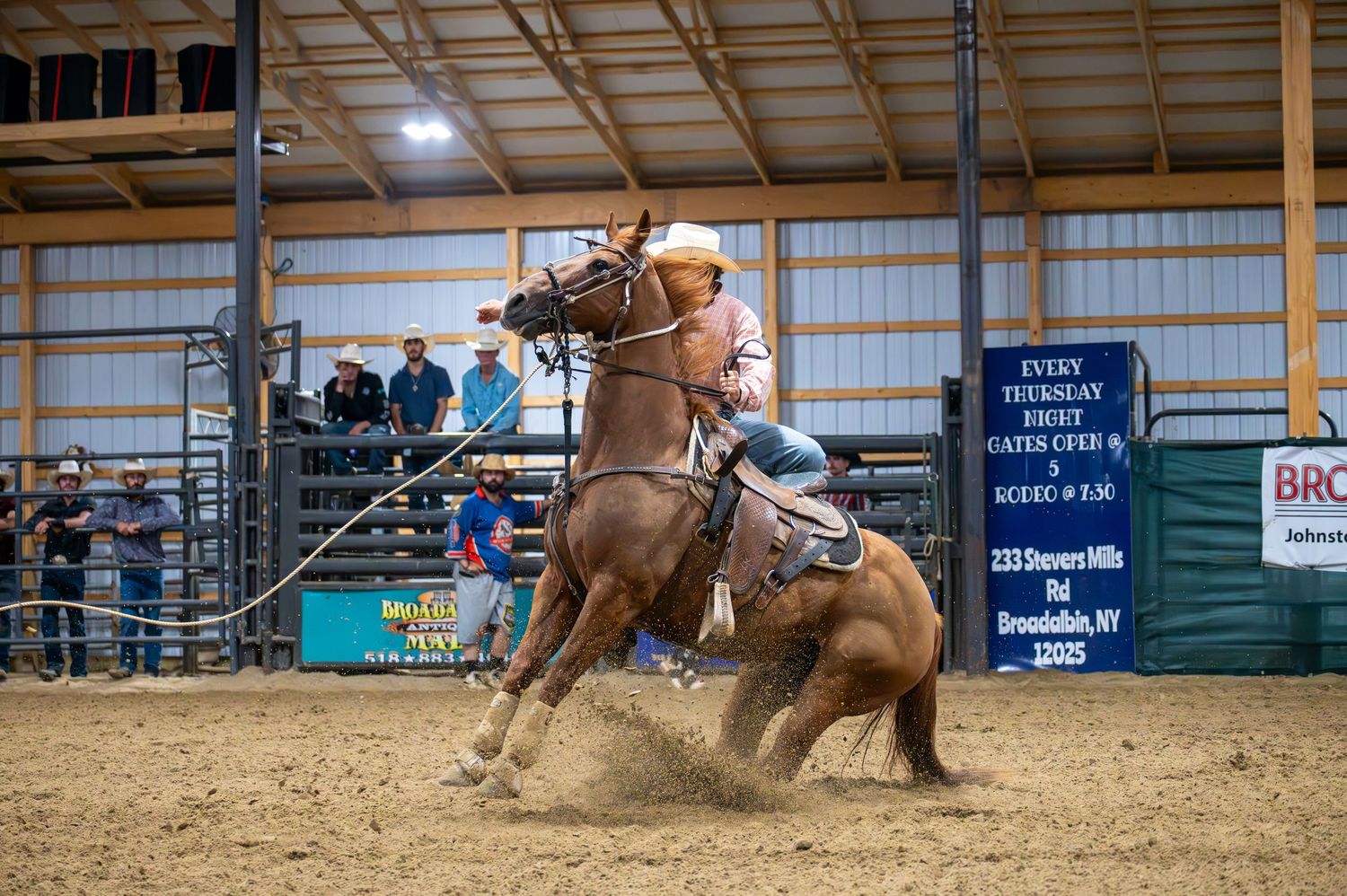 Wide shot of rodeo competition showing multiple riders in action across sandy arena floor.