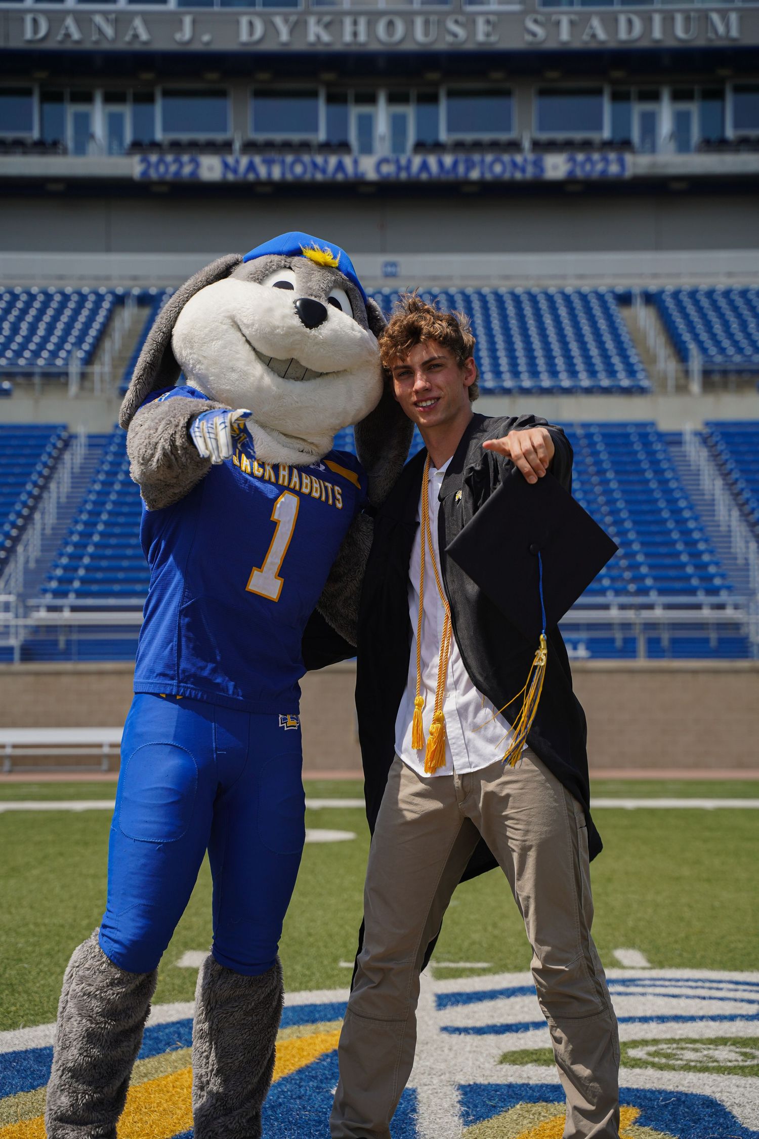 A portrait of a boy in a cap & gown next to South Dakota State University mascot, Jack, by Evan Patzwald Media.