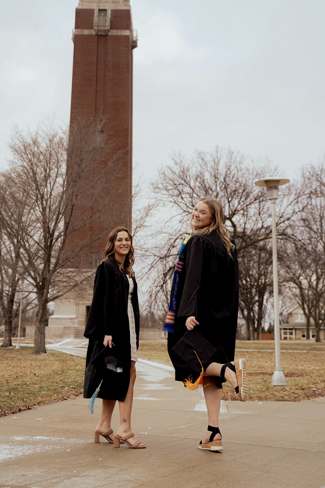 A portrait of two girls posing in a cap & gown by Evan Patzwald Media.