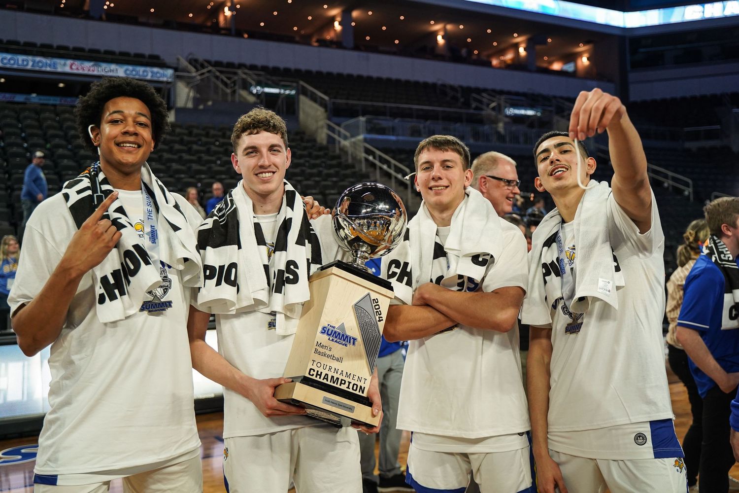 A photo of four South Dakota State University men's basketball players holding up a trophy by Evan Patzwald Media.