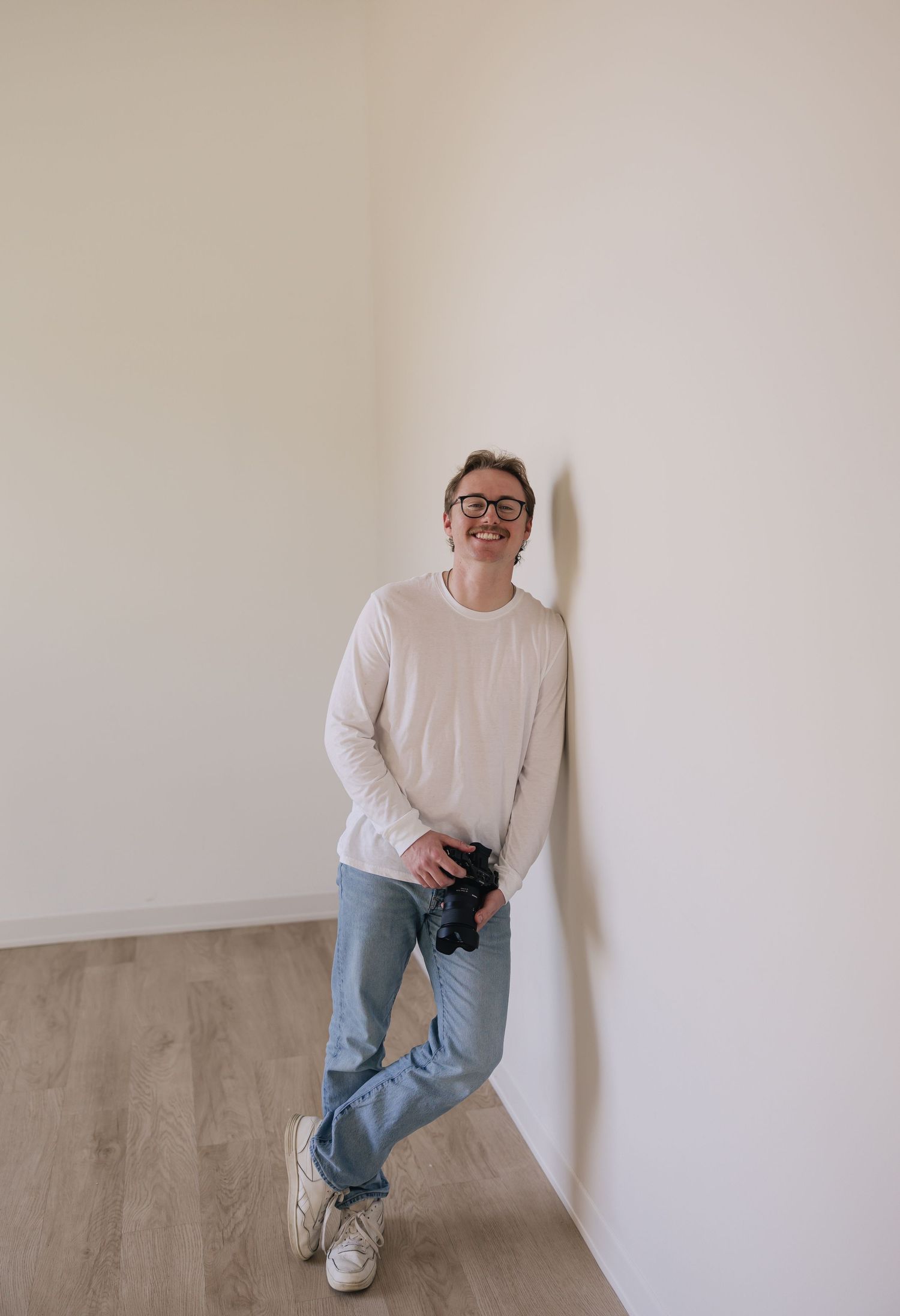 A portrait of Evan Patzwald holding a camera for Evan Patzwald Media.