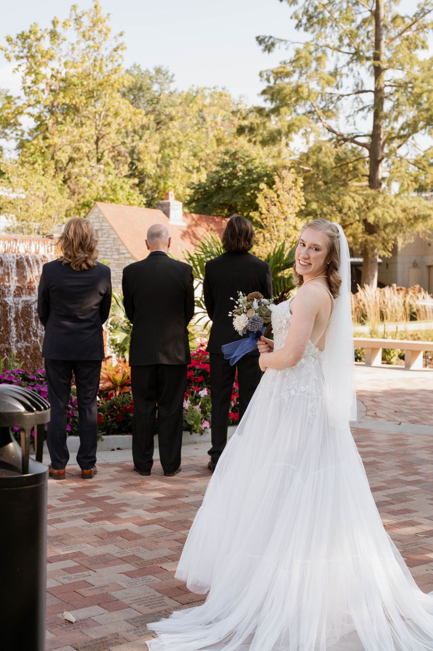 Bride looking back while brothers and father wait.