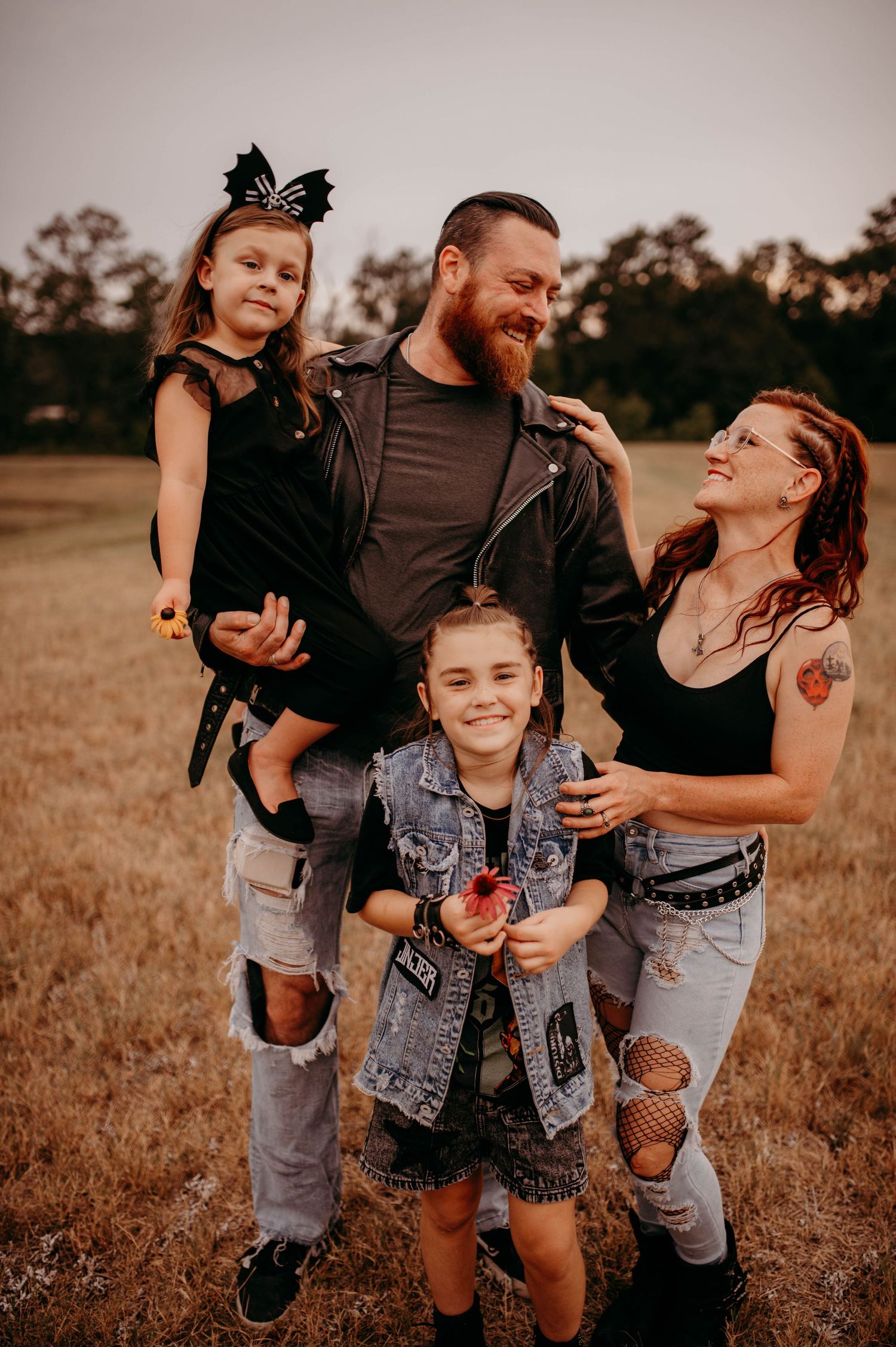 An alternative styled family laughing together in a field.