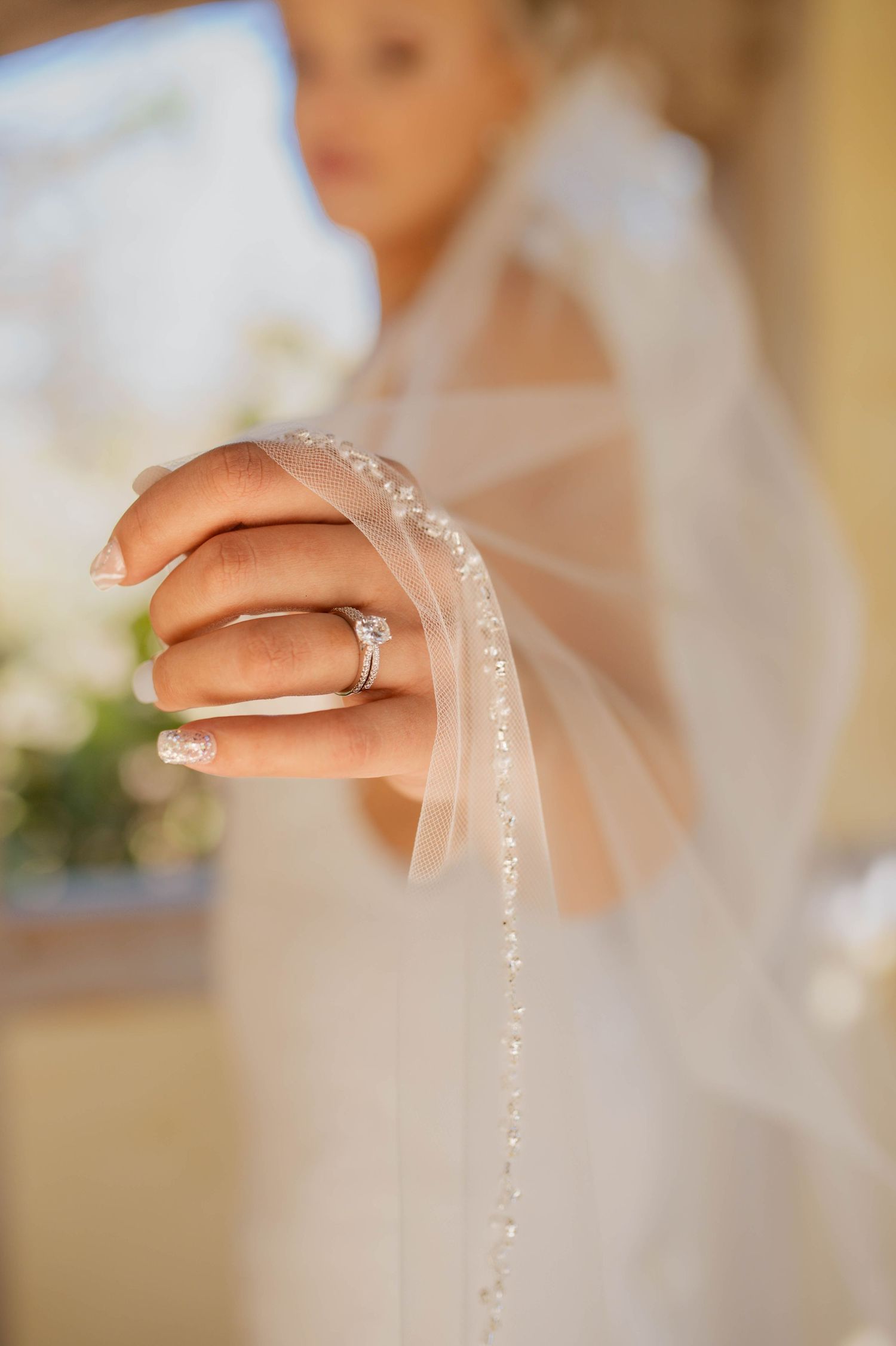 The wedding ring of a bride while she is holding her veil out.
