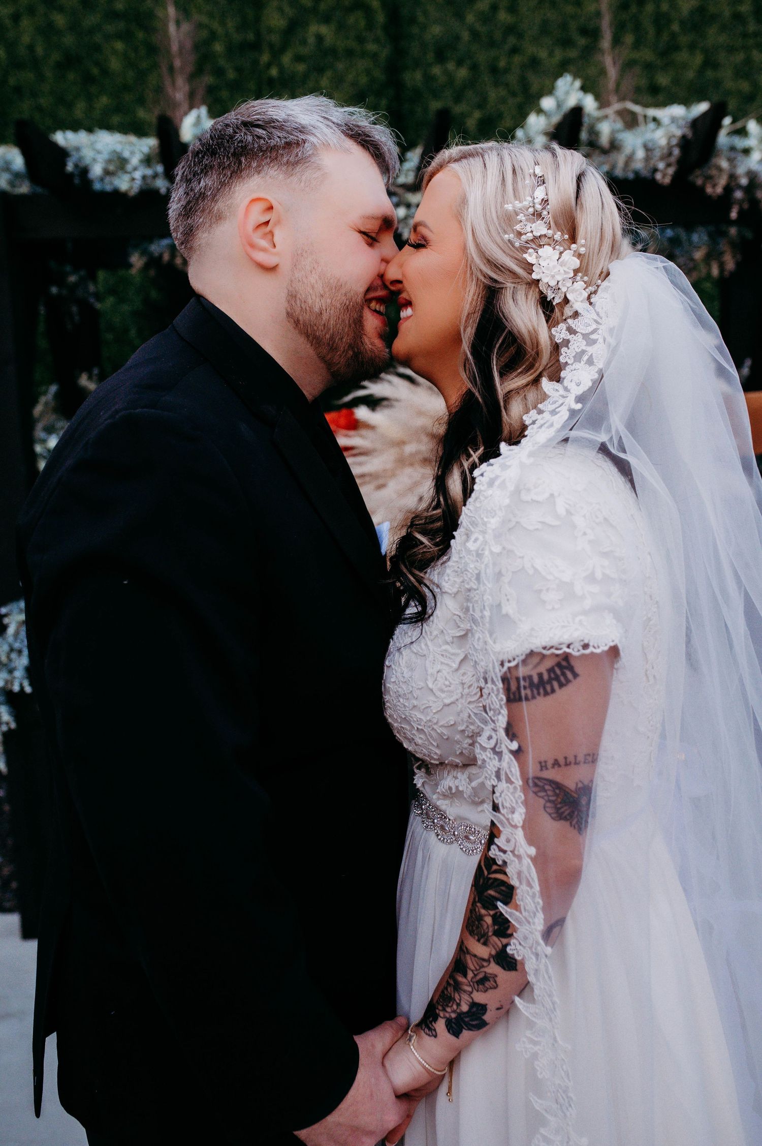 A bride and groom smiling and kissing.