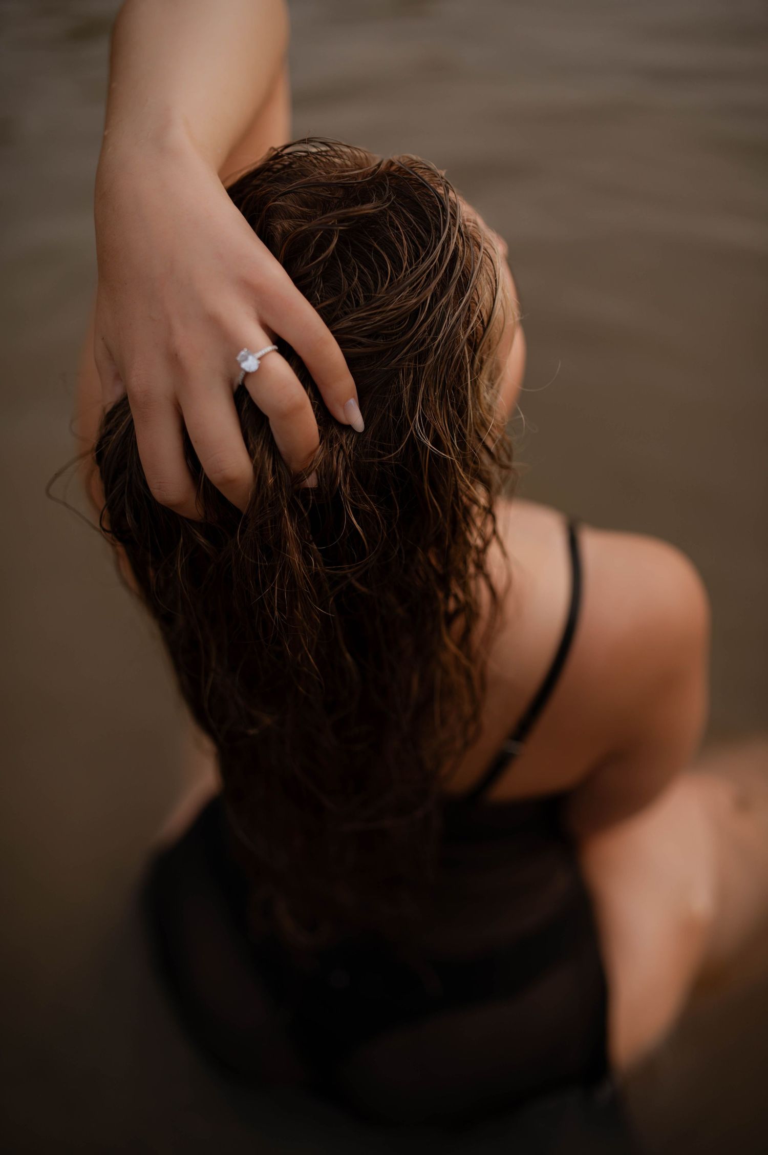 An engagement ring showcased on the hand of a woman in the water.