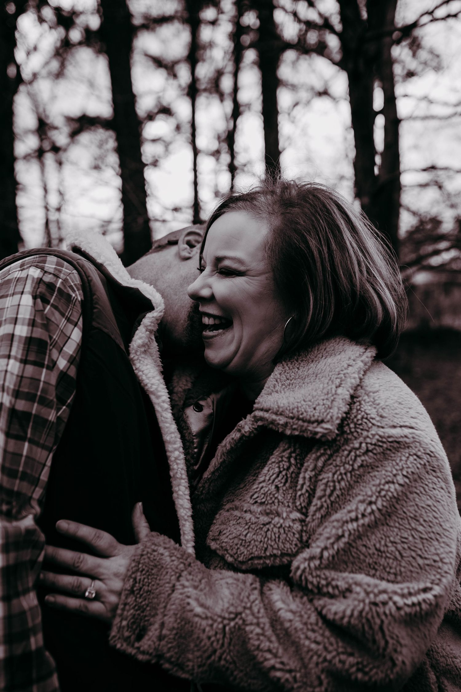 A woman laughing as a man snuggles into her.