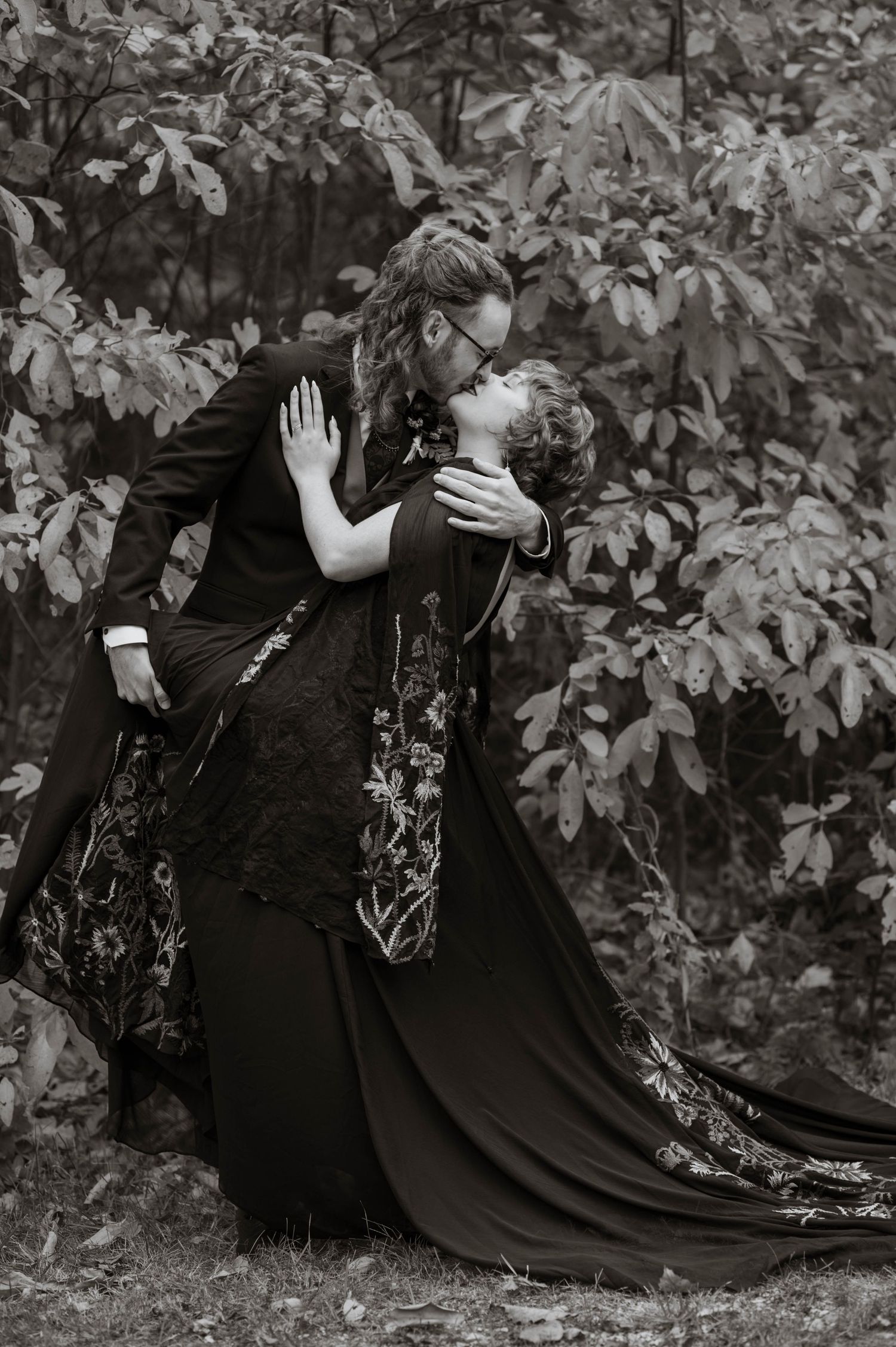 A groom dipping his bride and going in for a kiss.