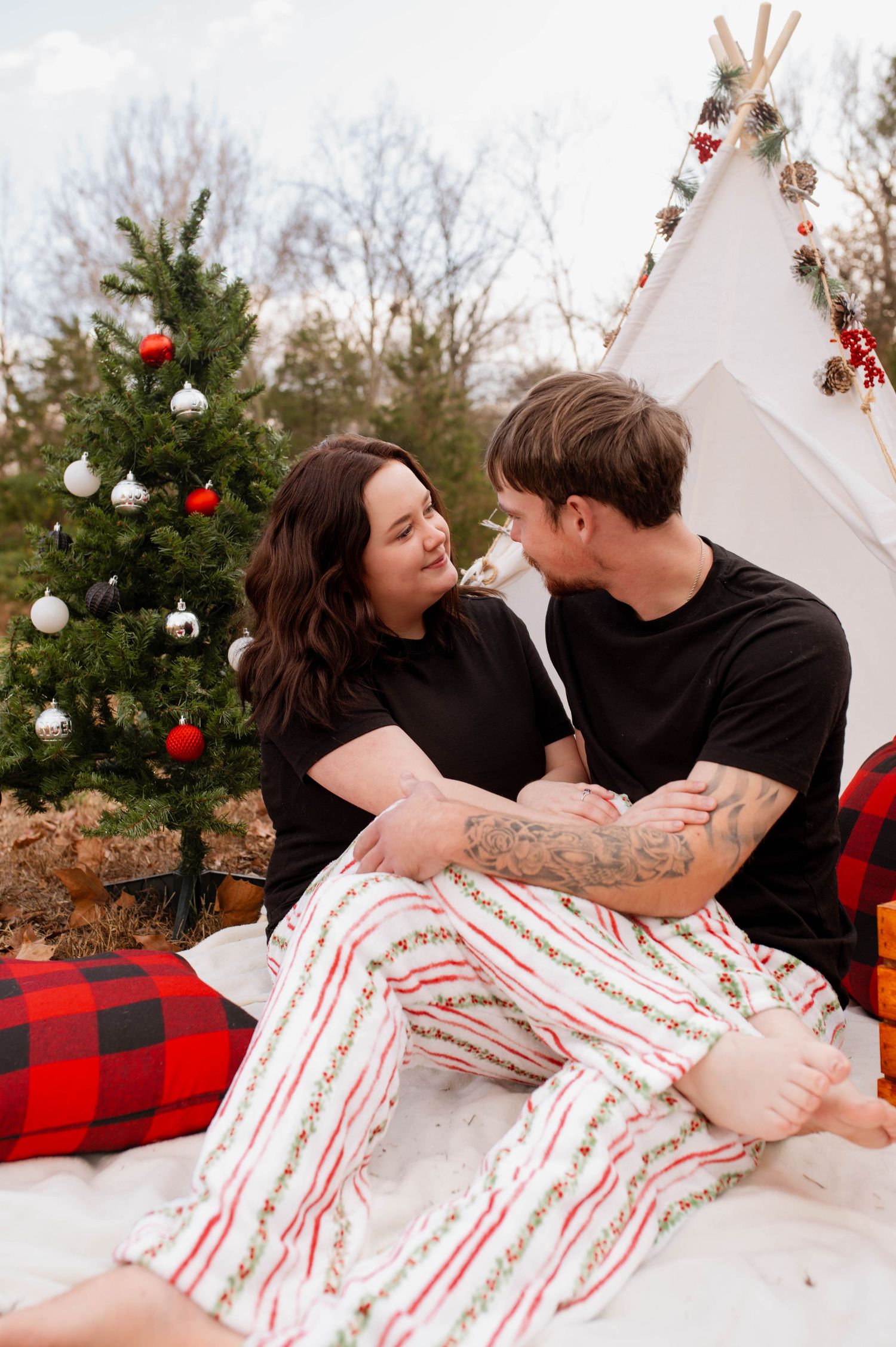A couple embracing one another in front of a Christmas tree.