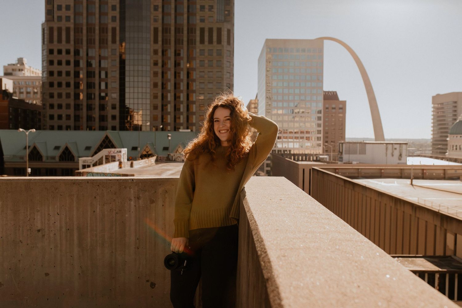 A woman holding a camera while playing with her hair