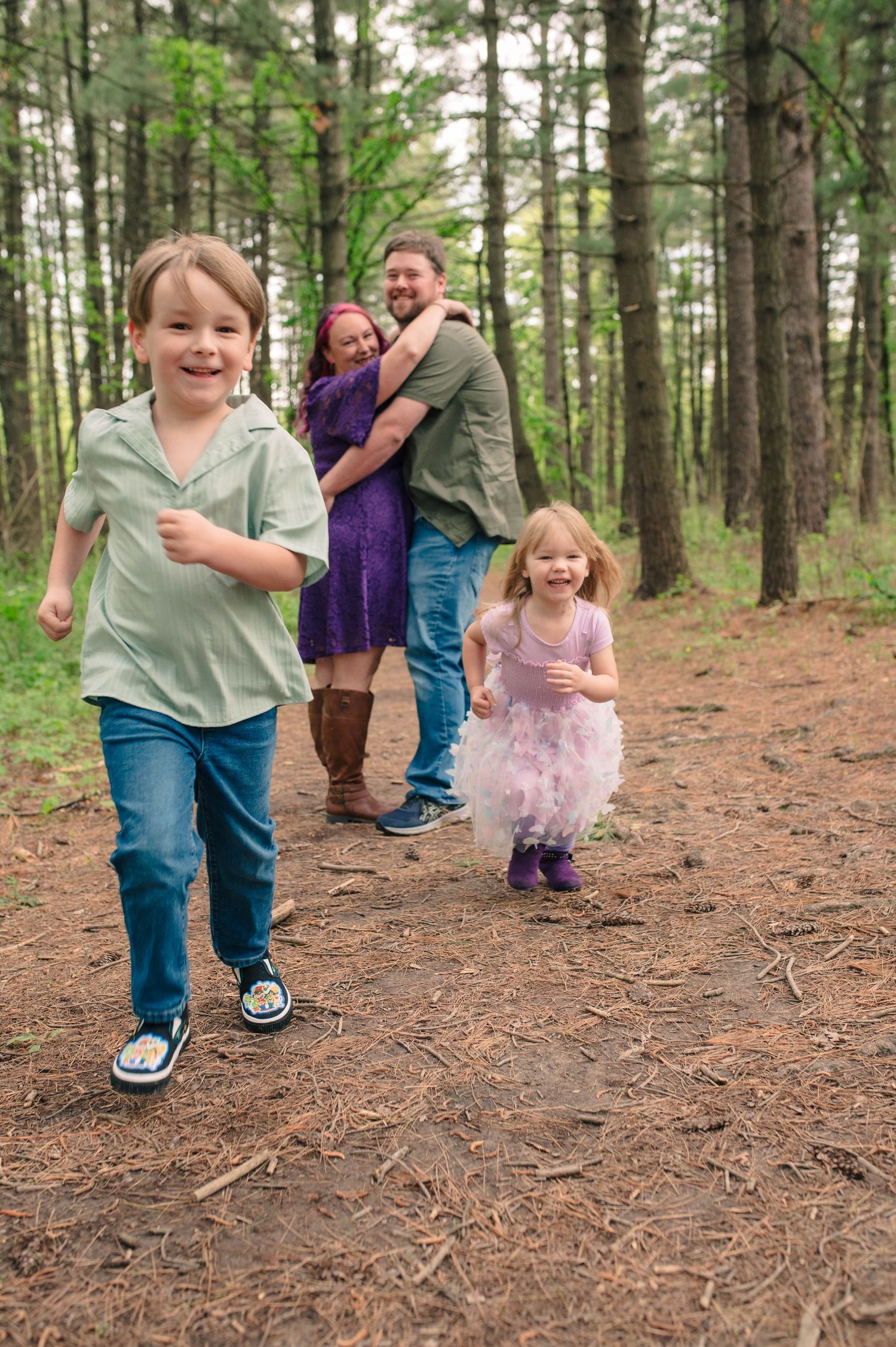 A mom and dad looking at their children while they run and laugh.