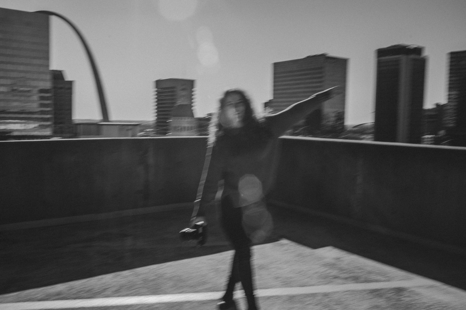 A woman holding a camera walking on top of a building