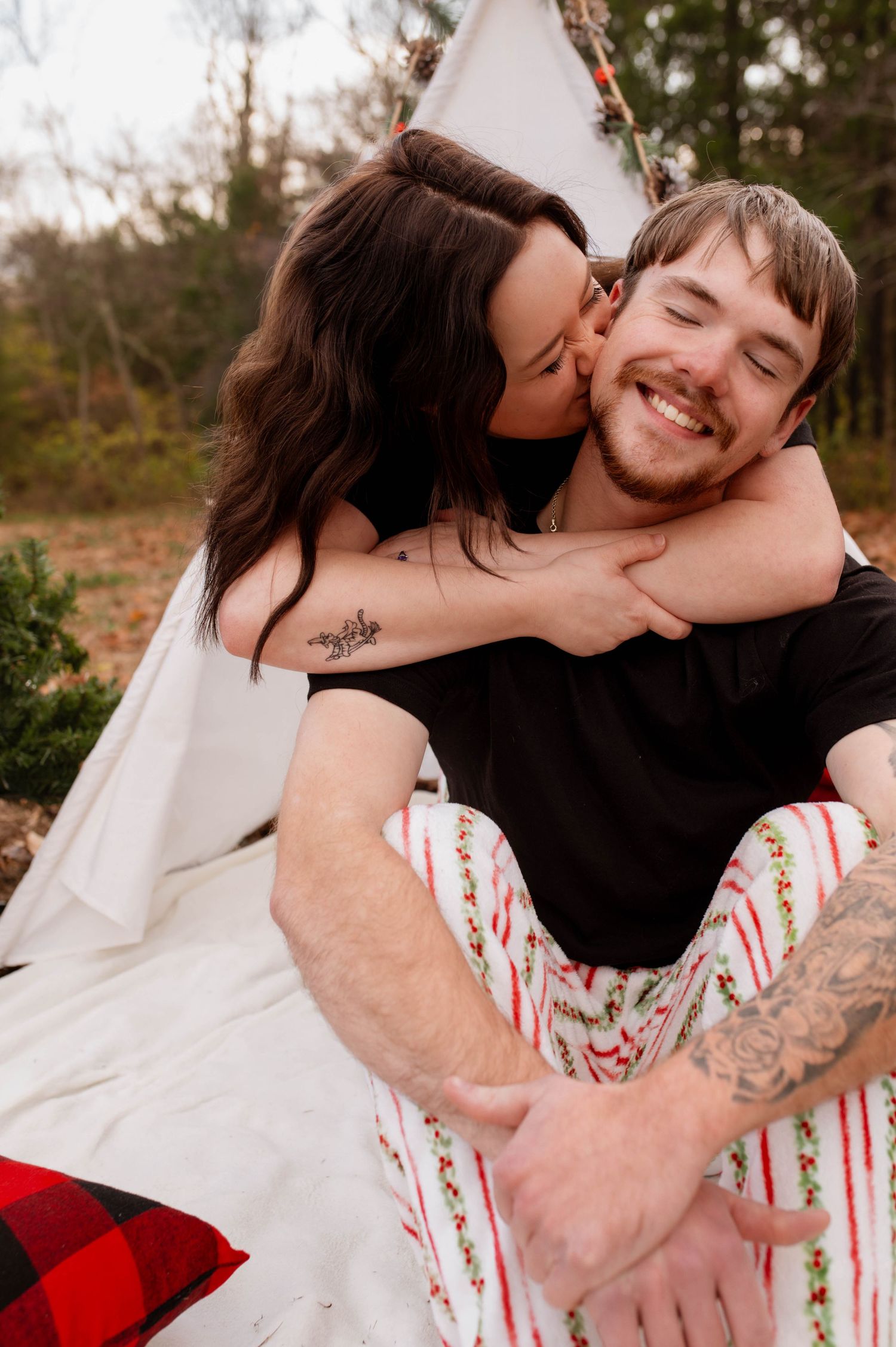 A woman kissing her partner on the cheek while he laughs.