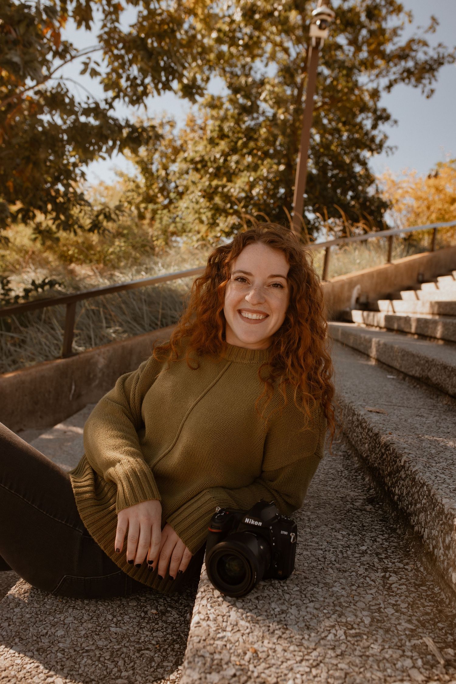 A woman on stairs with a camera in front of her.