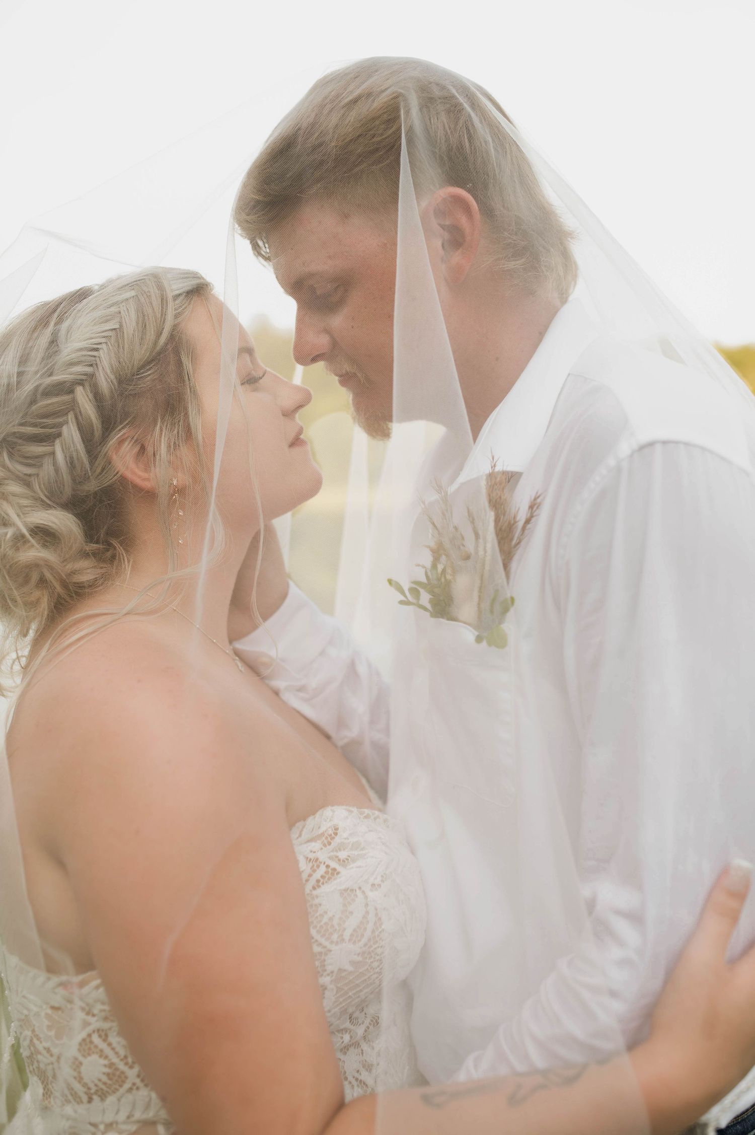 A bride and groom smiling under her veil.