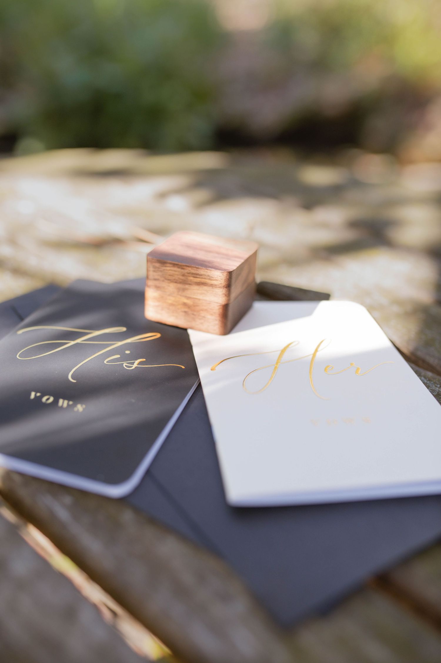 His and Hers vow books and a wooden ring box.