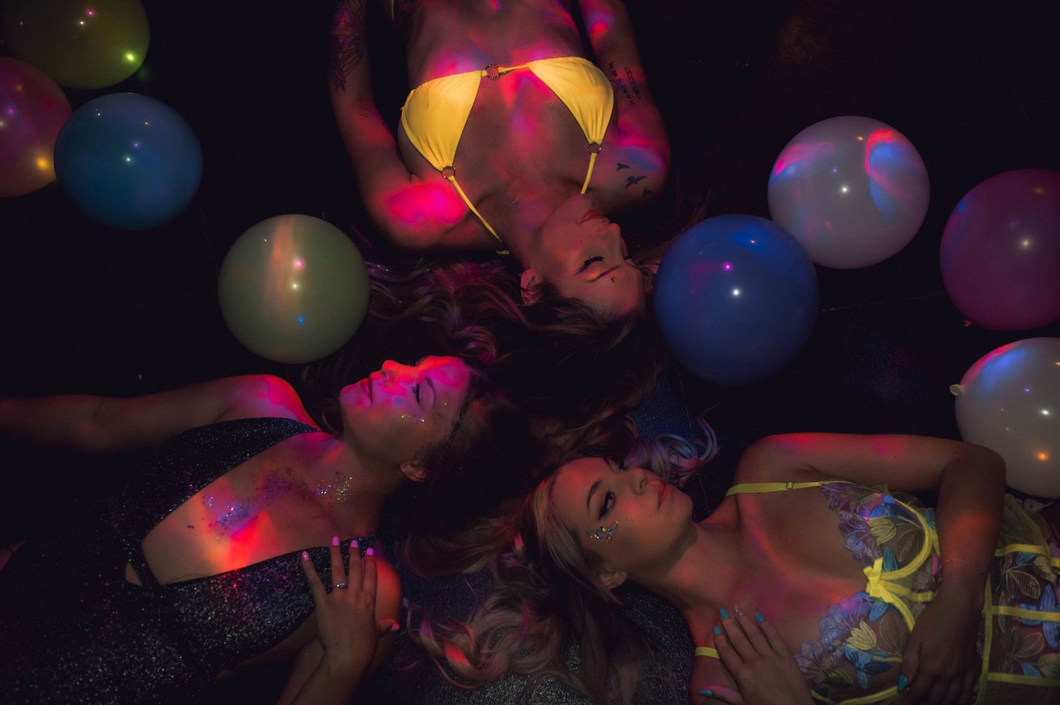 3 women laying on the ground in lingerie