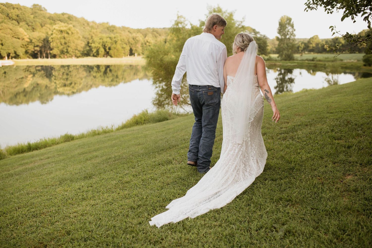 A bride and groom walking in front of water.