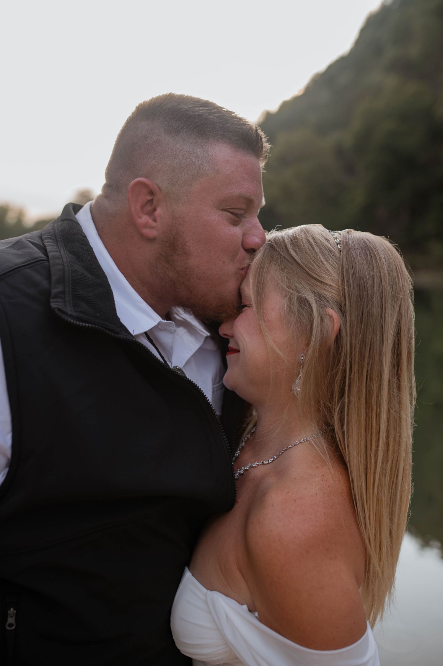 A groom kissing his bride's head.