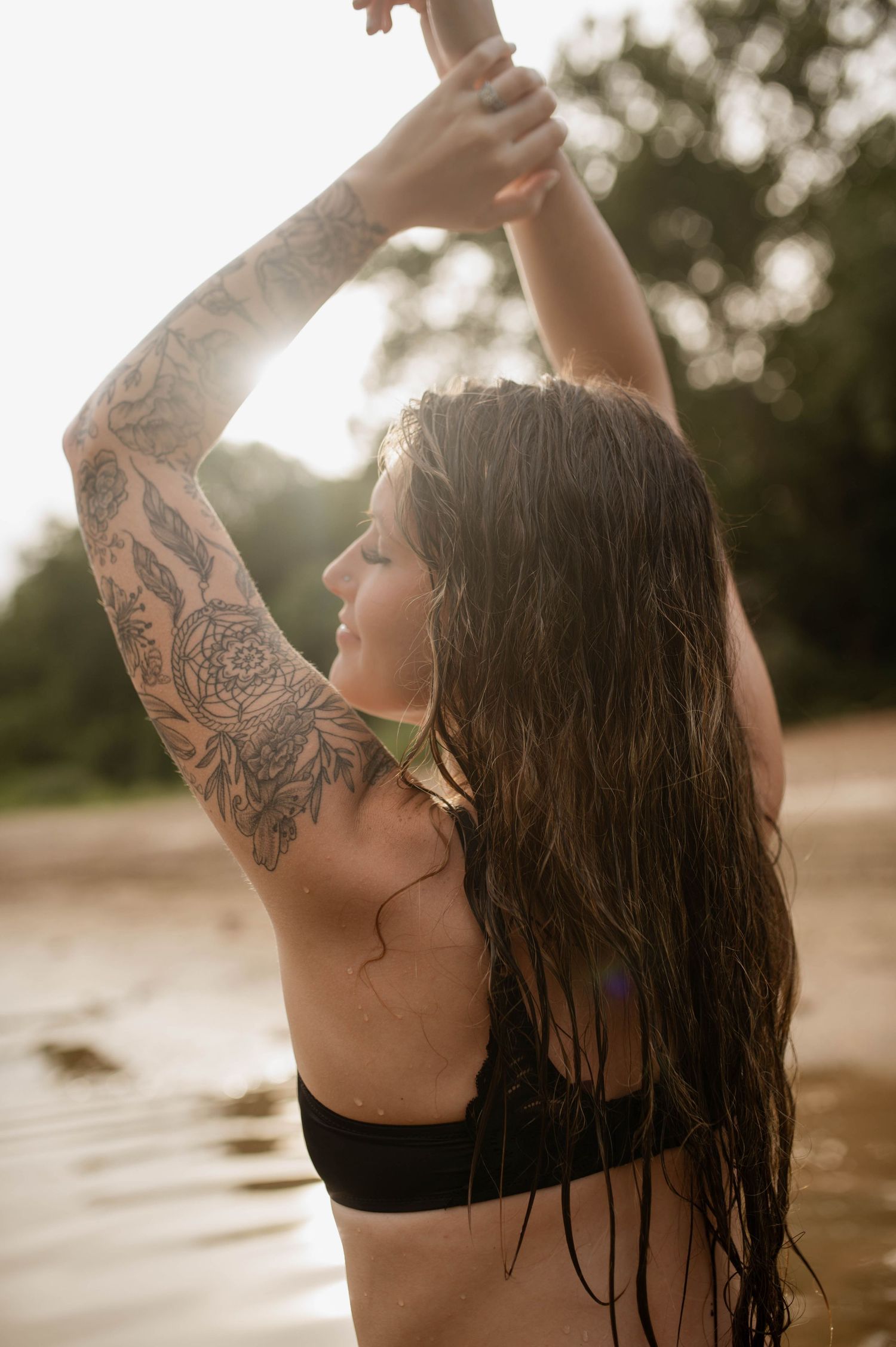 A woman with her arms up and the sun beaming down on her face.