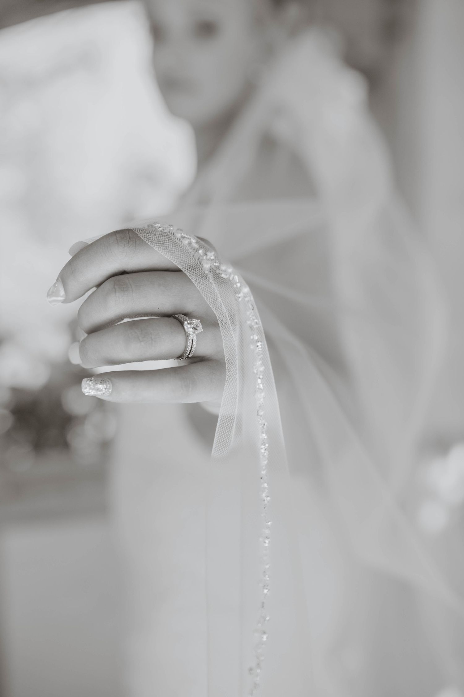 A bride holding her veil out, focusing on her ring.
