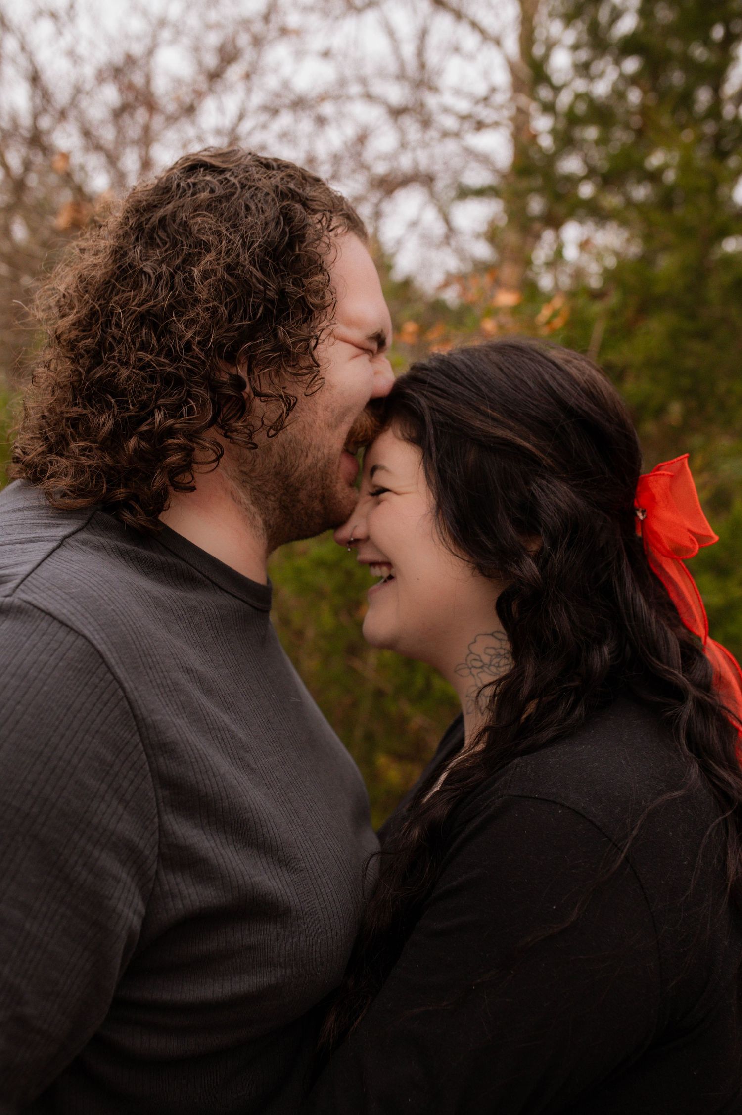 A man kissing a woman on her forehead while she laughs.