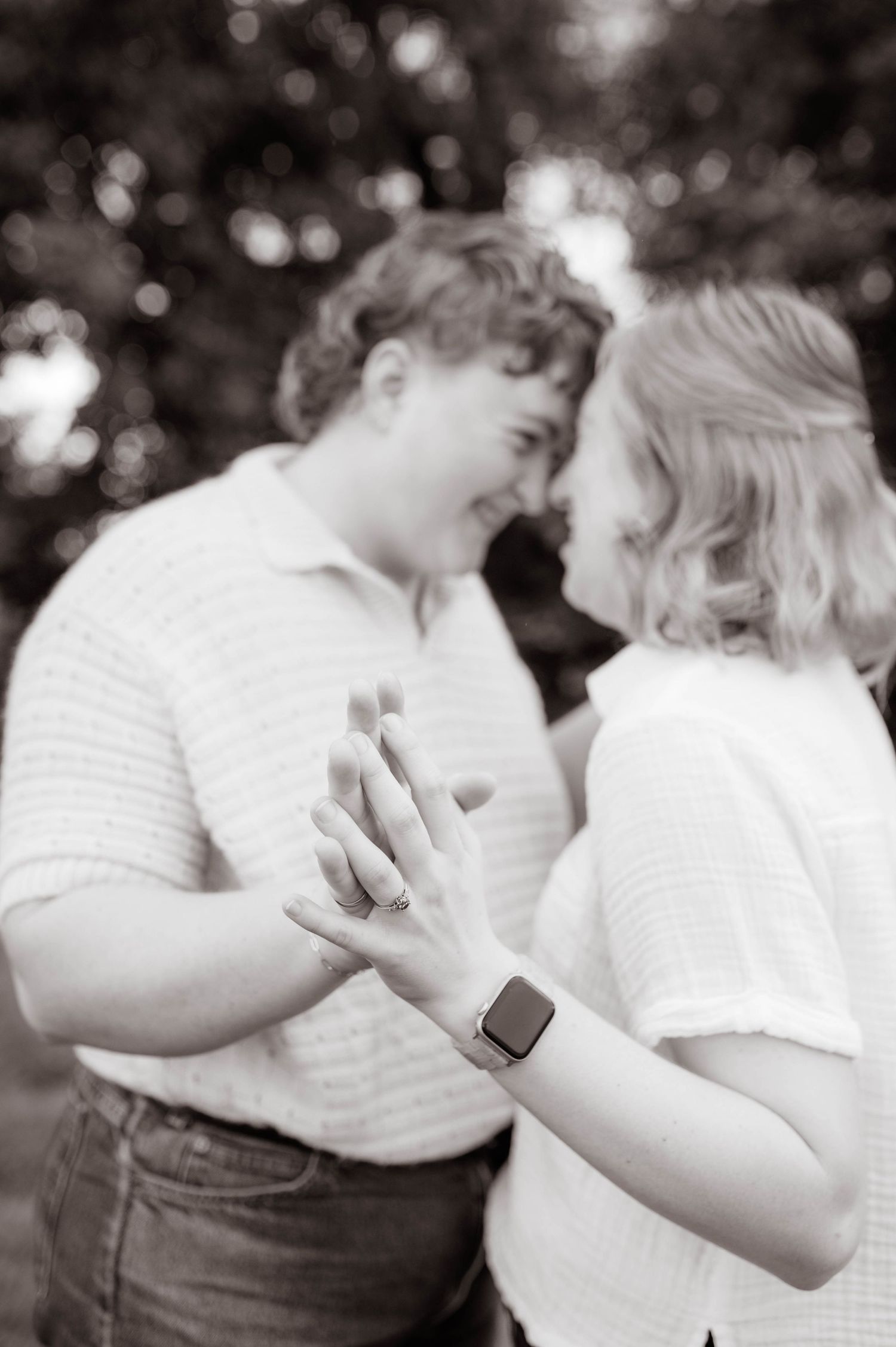Two engaged people holding hands, forehead to forehead.