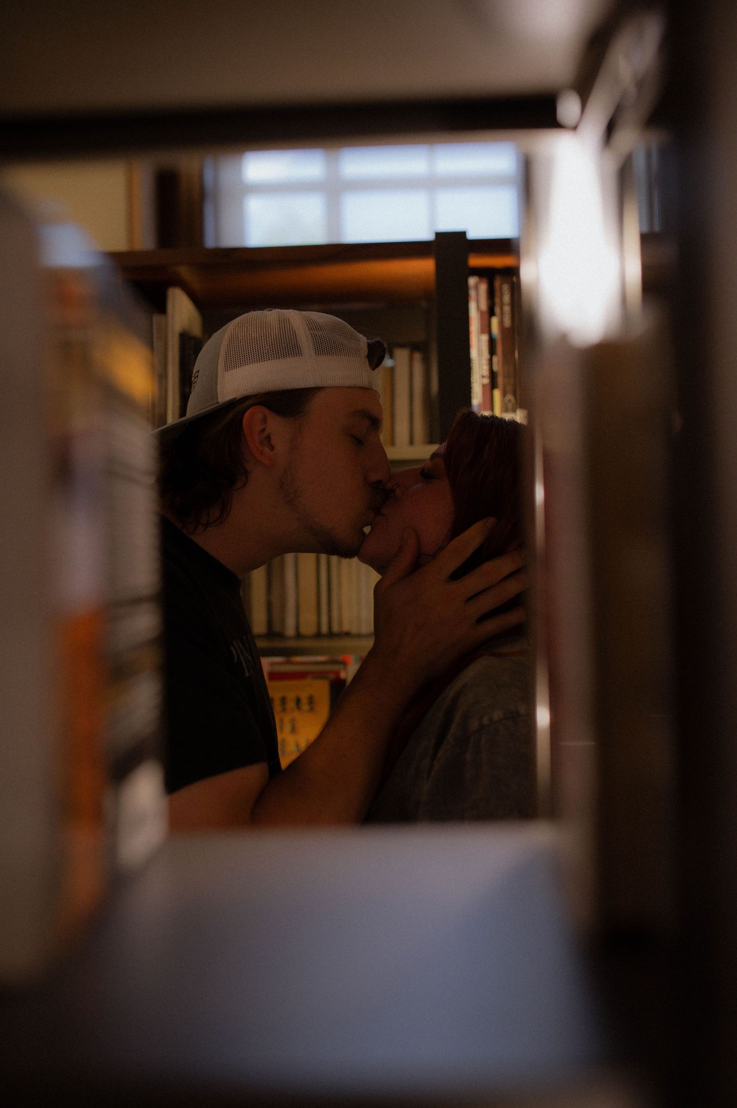 A couple kissing in a library.