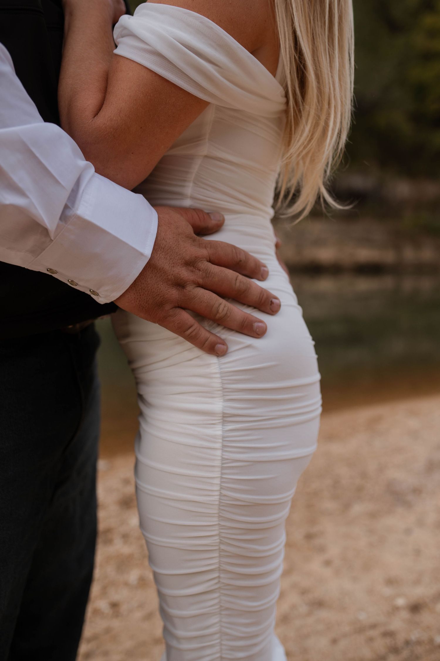 The hands of a groom on the hips on his bride.