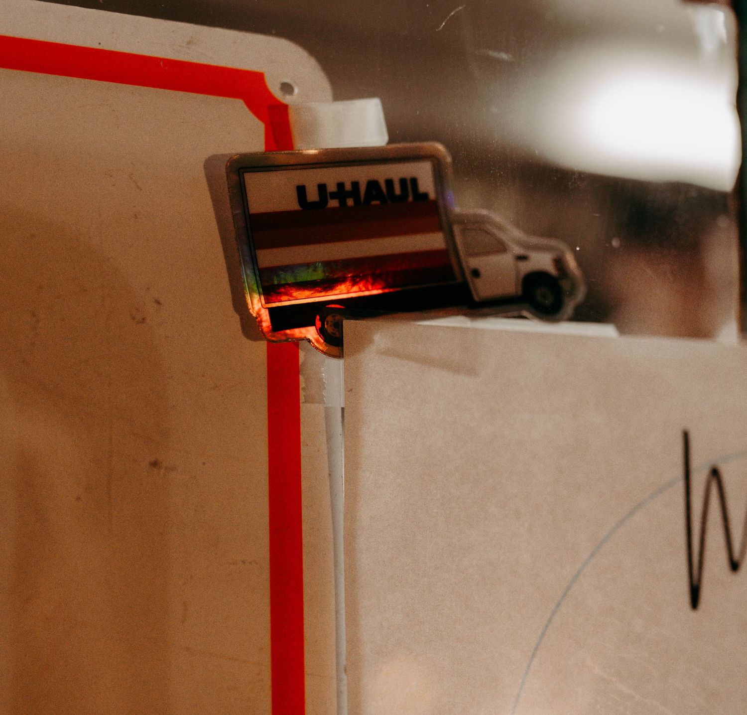 A UHaul sticker inside of a food truck, with lesbian pride flag colors on it.