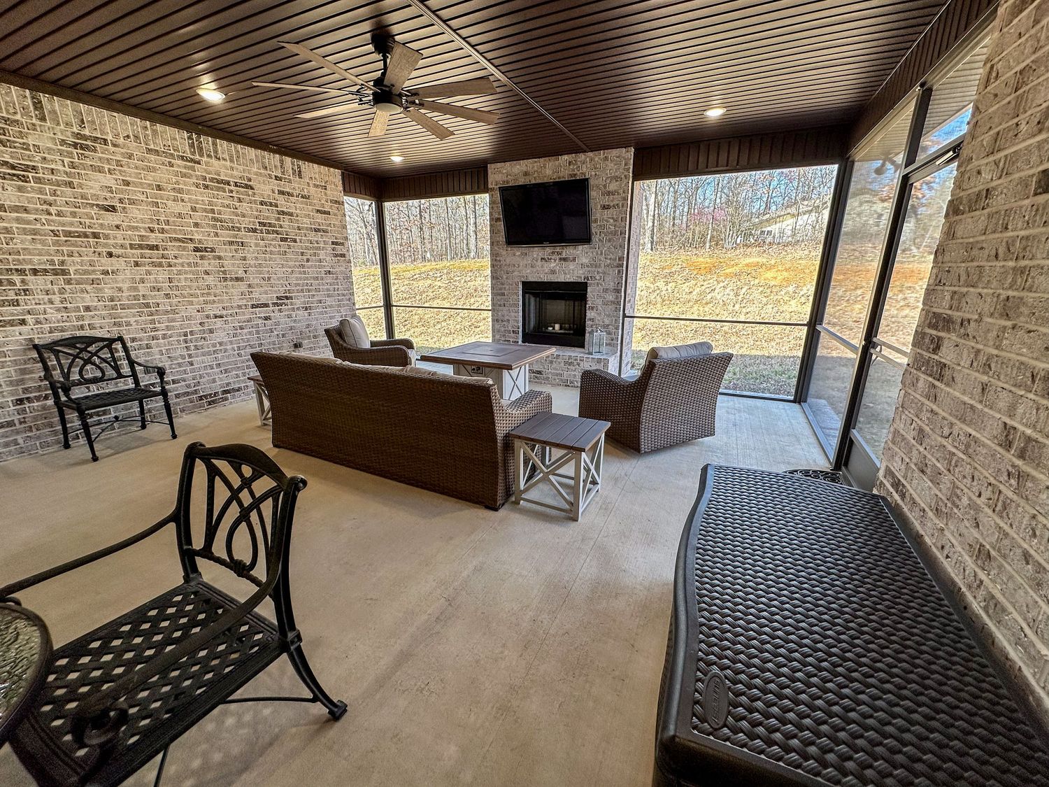 Covered patio with stone walls and black metal outdoor furniture arranged for comfortable seating.