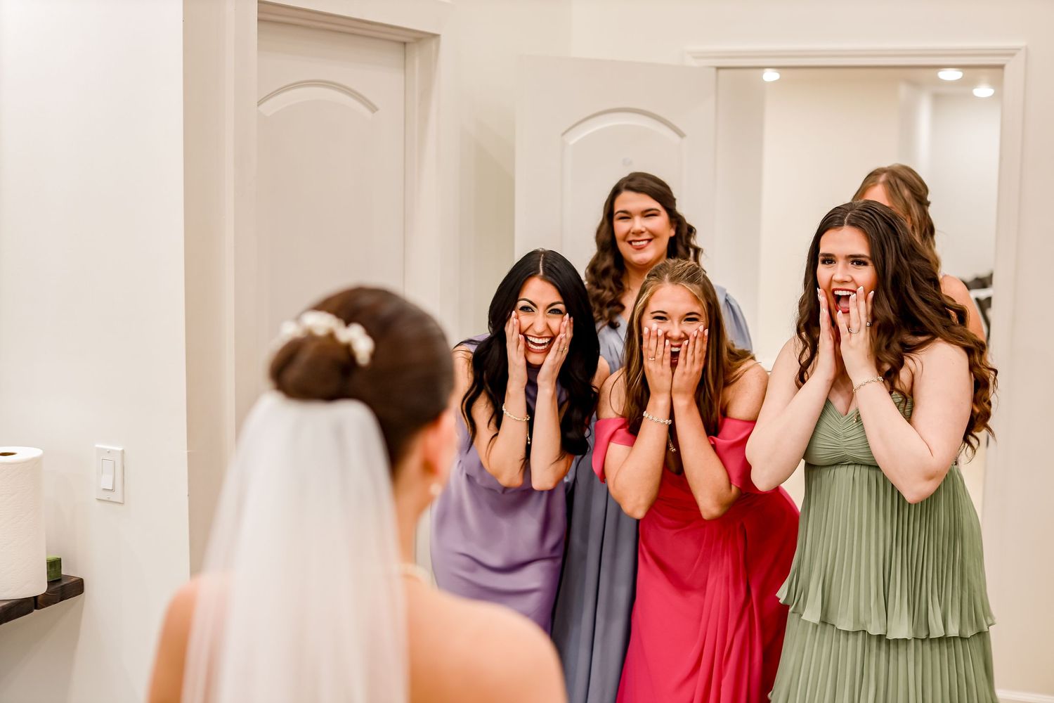 Wedding party reacting with excitement and surprise in an indoor setting.