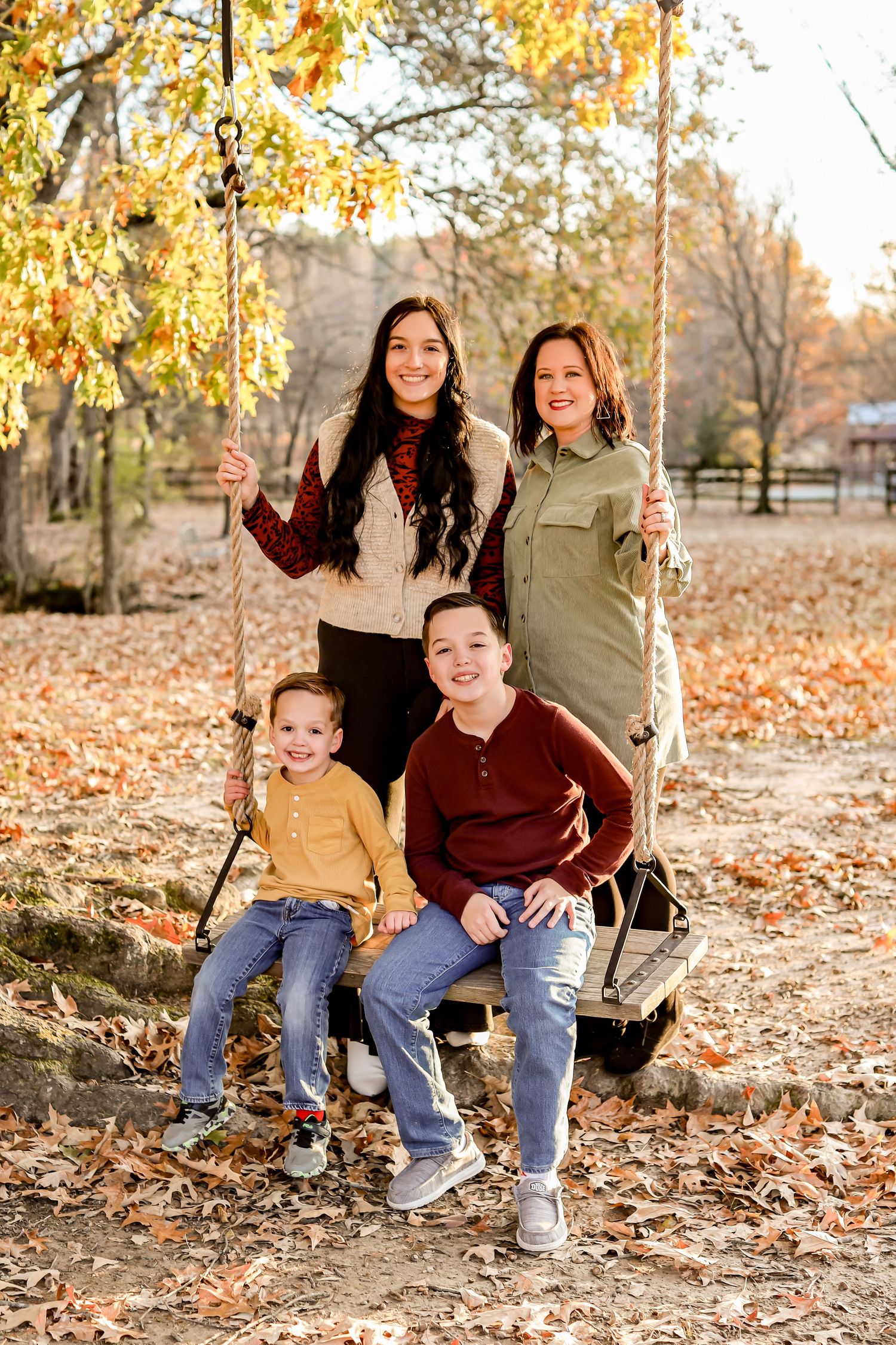 Group enjoying a fall day on a wooden swing surrounded by autumn foliage.